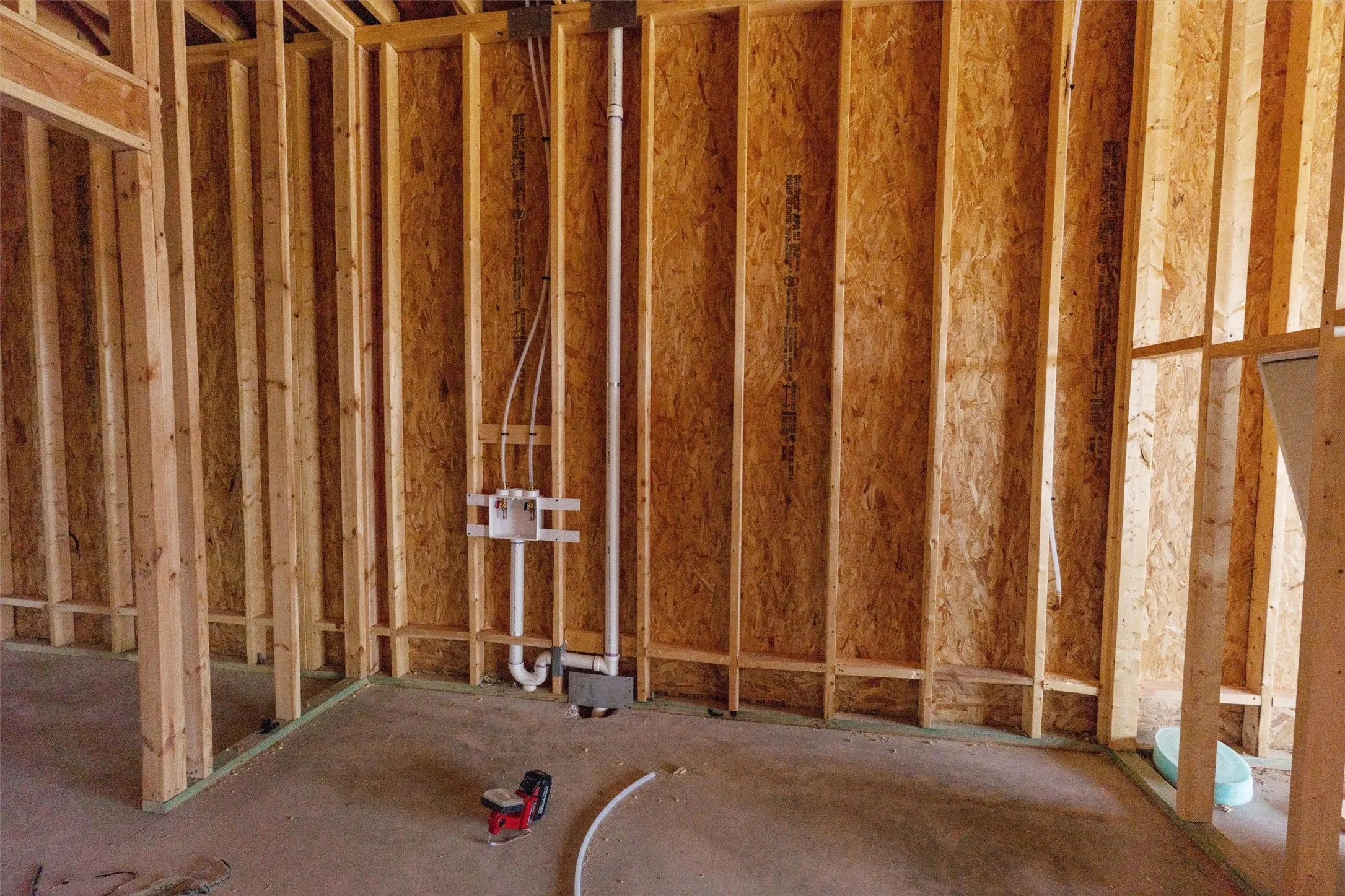 Framed interior walls with exposed OSB sheathing and visible plumbing rough-ins