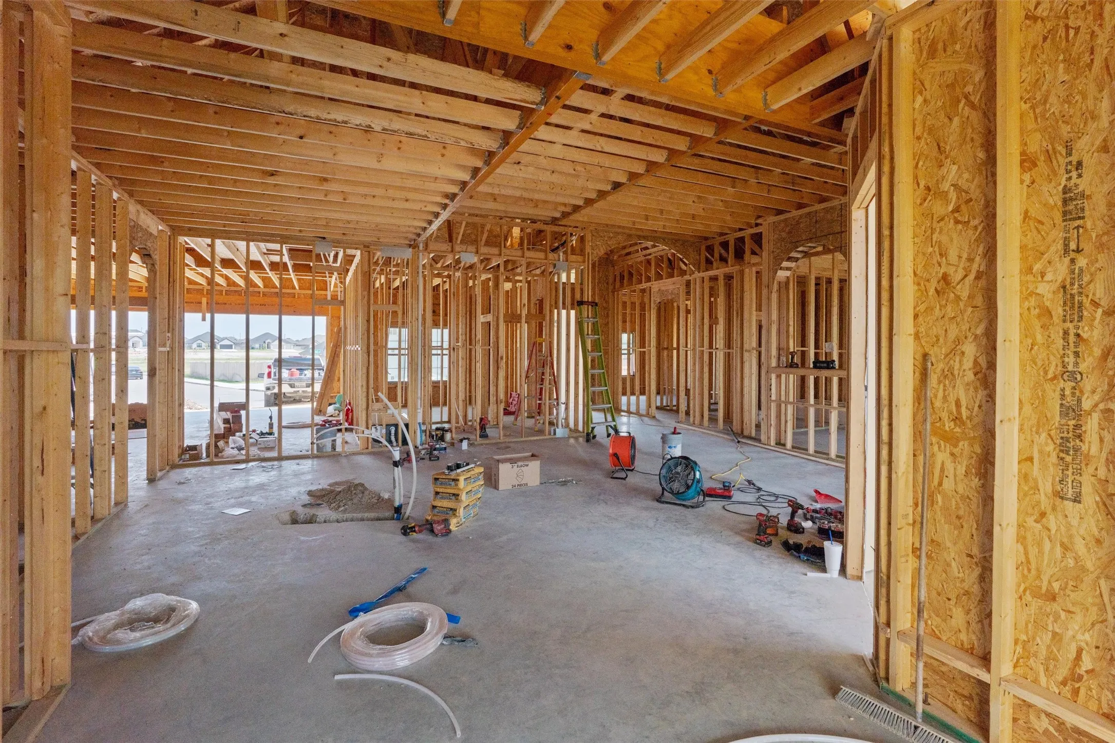 New construction framing with wood studs, concrete slab foundation, and open ceiling joists