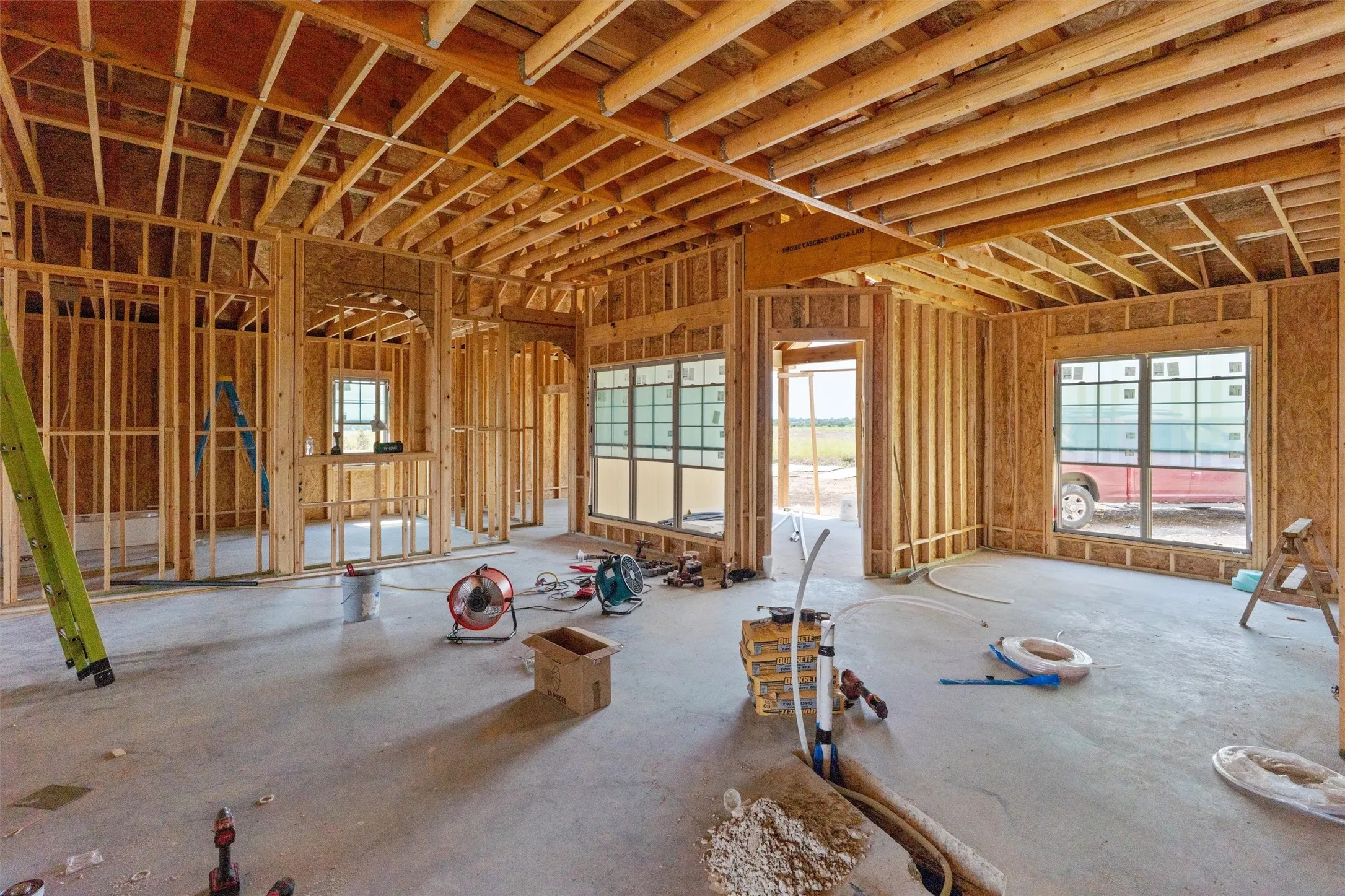 Interior framing showcasing open floor plan, multiple windows, and exposed ceiling joists