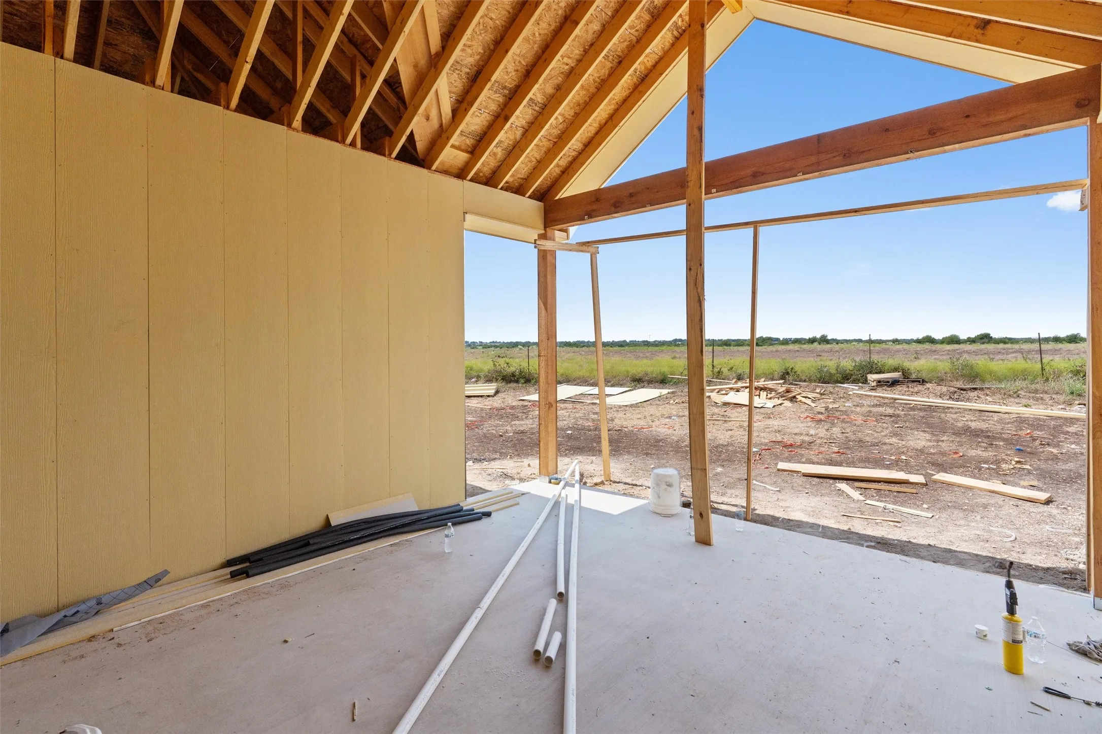 Exposed wooden roof trusses and framing, concrete slab foundation, and open wall framing