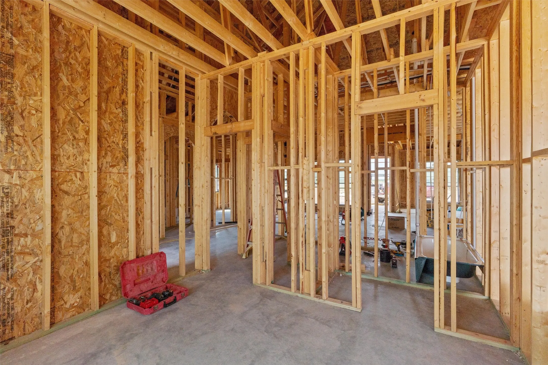 New construction framing with exposed wood studs, oriented strand board (OSB) sheathing, and a concrete slab foundation