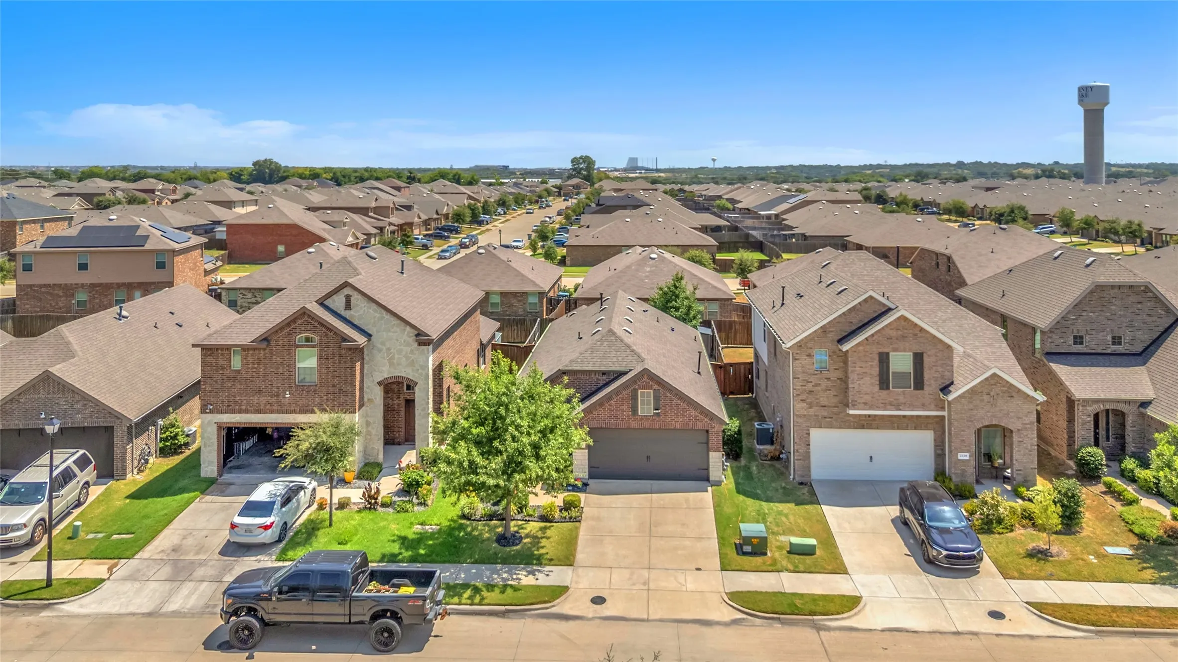 Residential neighborhood with single-family homes, brick and stucco exteriors, asphalt shingles, organized layout, and visible greenery in yards.
