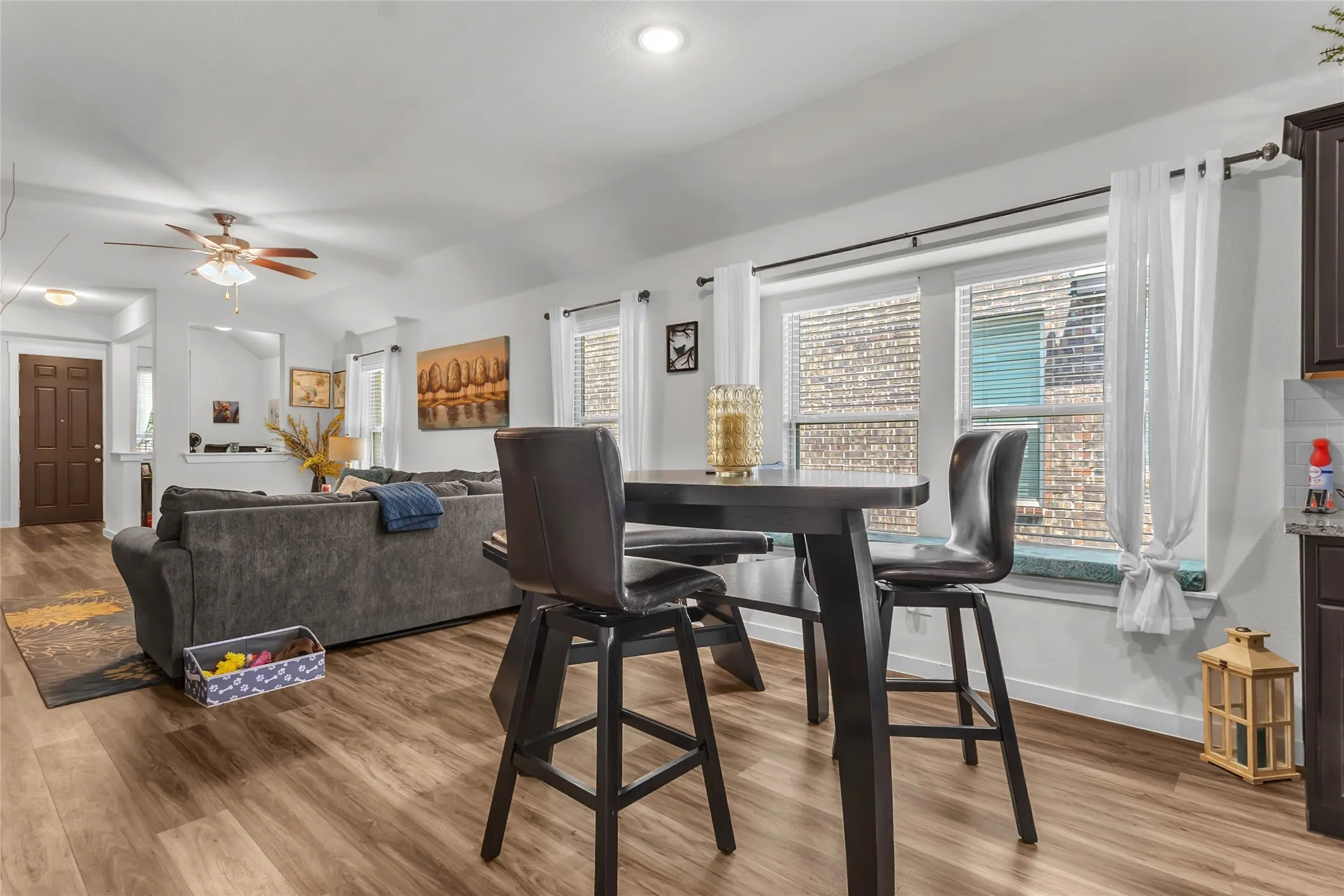 Open-plan living area with hardwood flooring, large windows providing natural light, and a combination of modern furniture and decor.