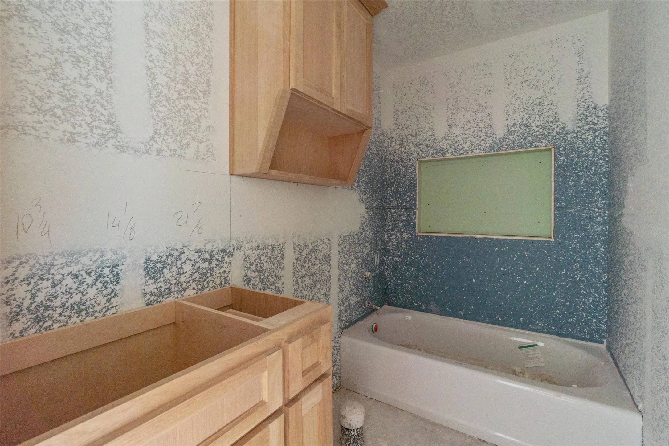 Unfinished wood cabinetry, built-in wall cabinet, recessed wall niche, and an unfinished bathtub