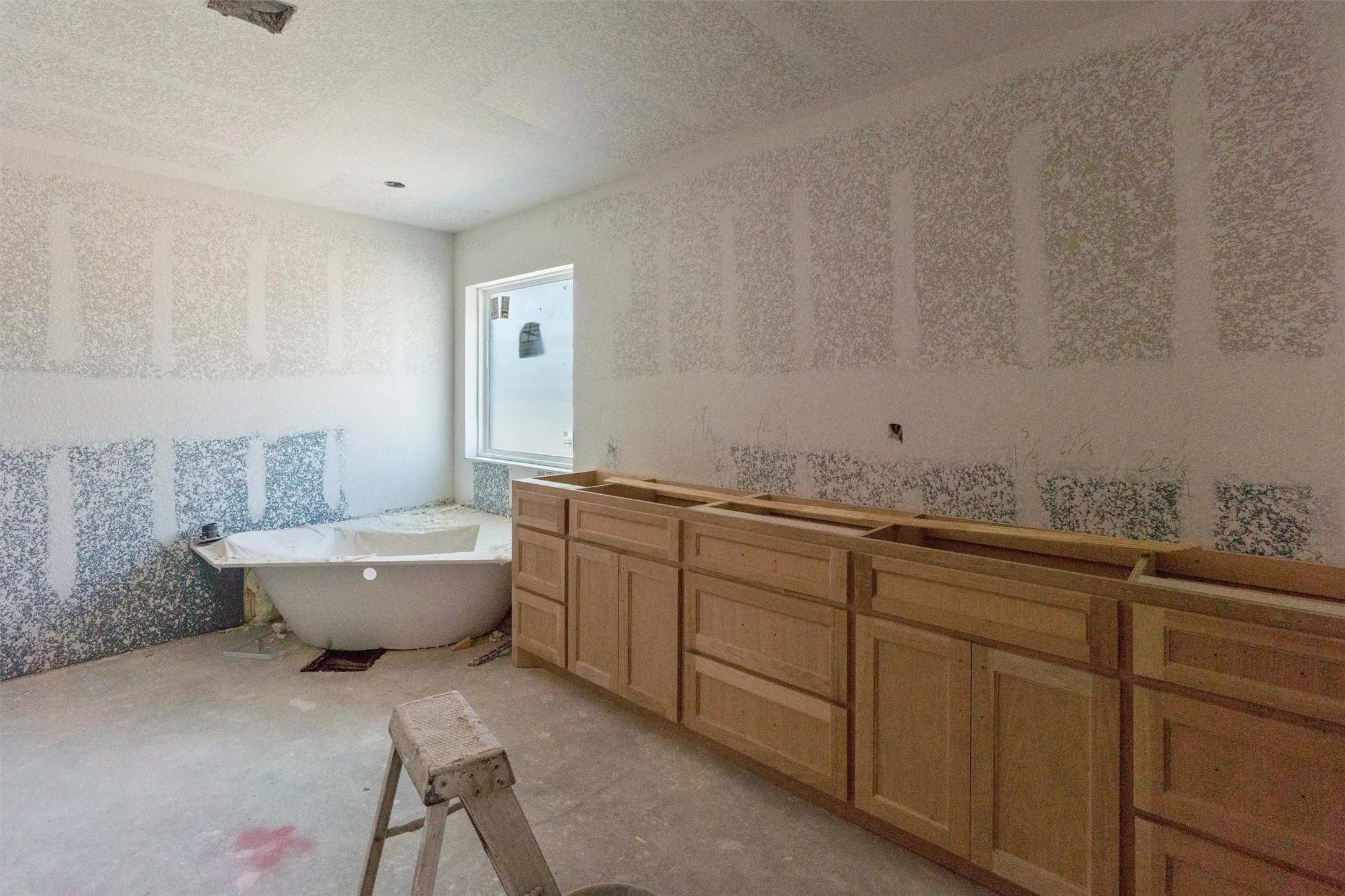 Freestanding soaking tub, window, and extensive cabinetry