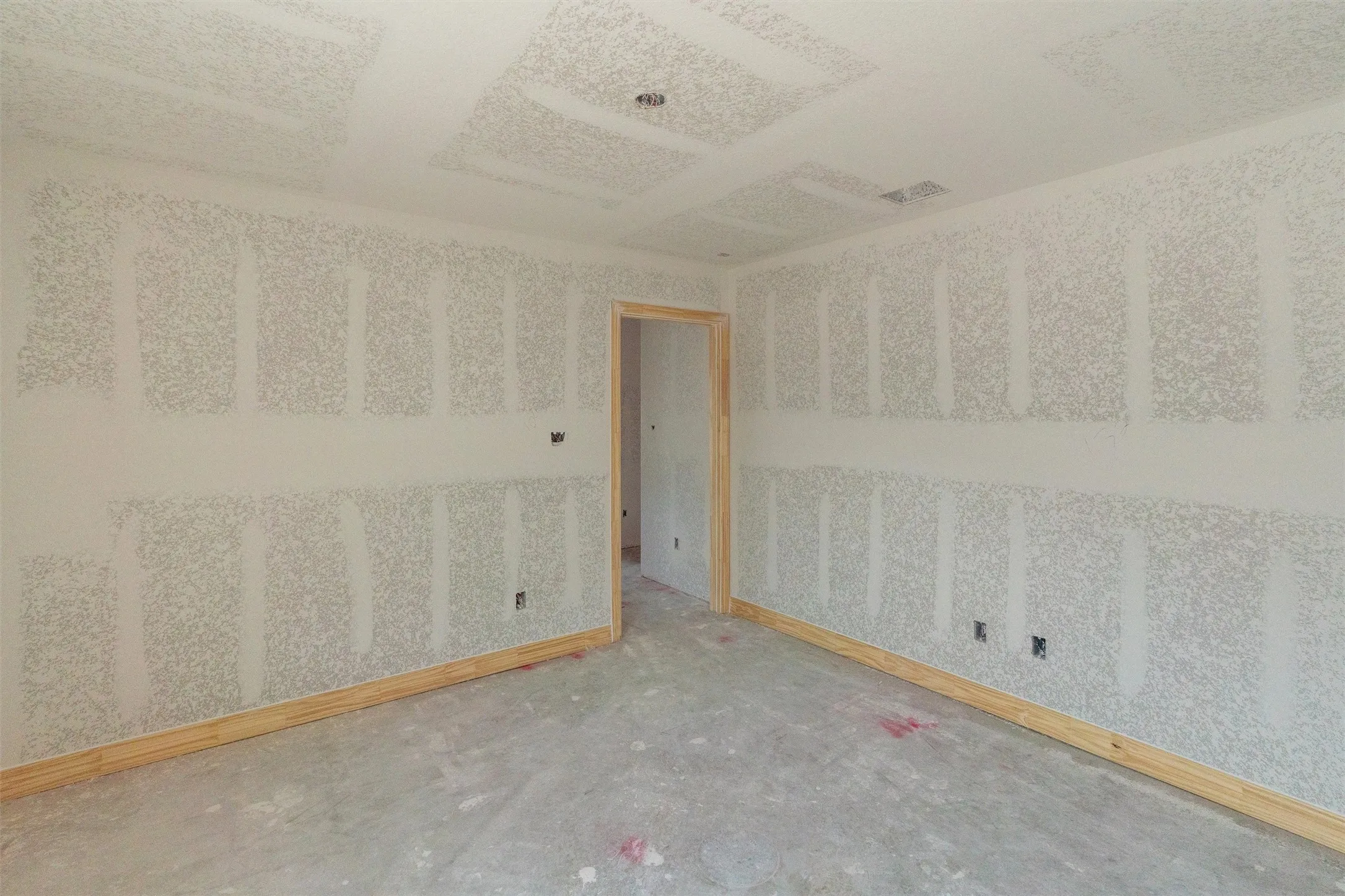 Unfinished interior space with drywall installation, wood trim accents, and ceiling texture