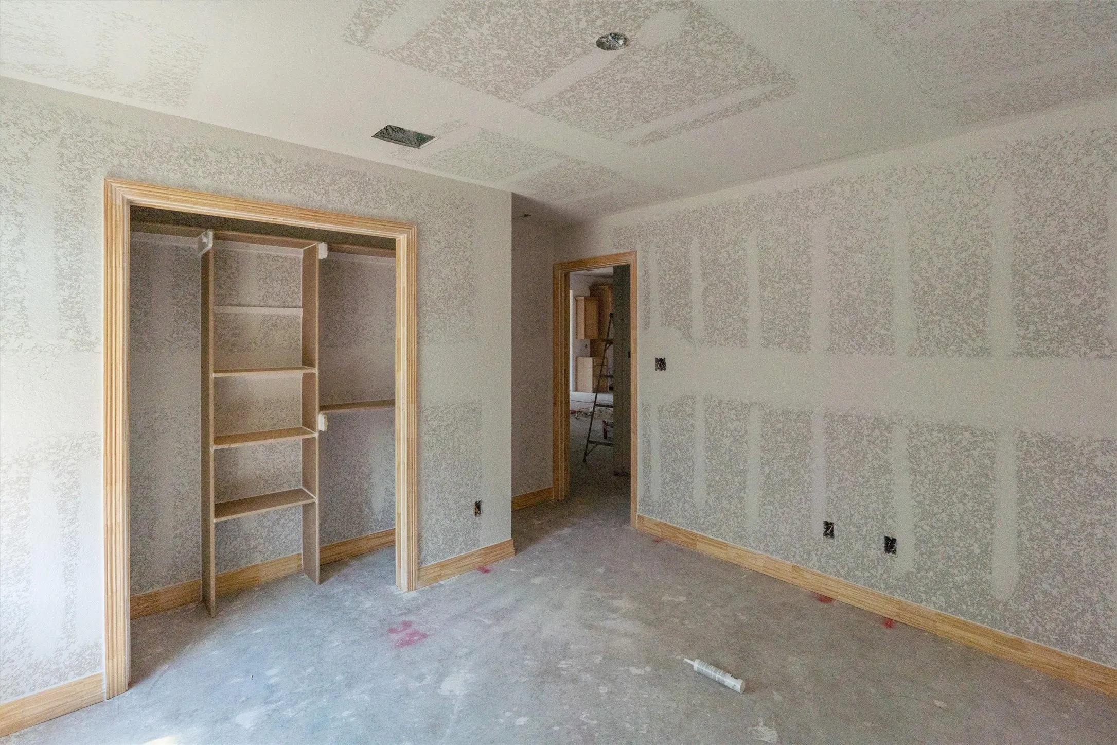 Unfinished interior room featuring a built-in closet with shelving, wood-finish door frames, wood-finish trim, and recessed lighting