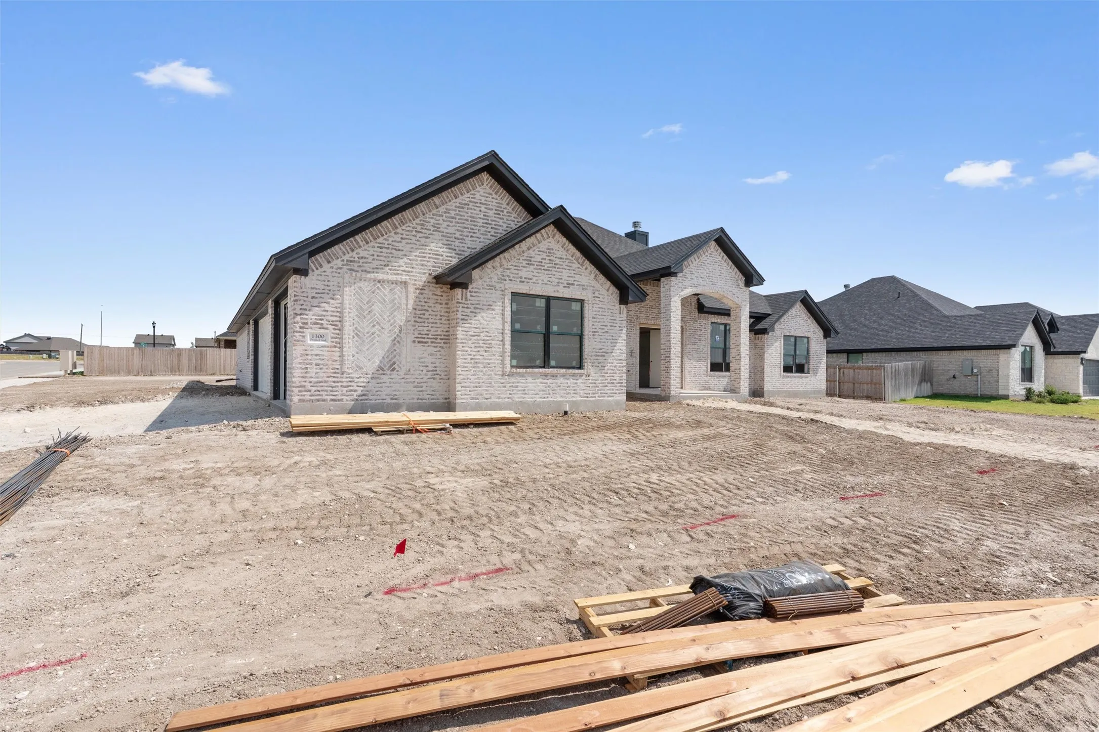 New construction residence featuring a light-colored brick exterior, dark shingles, and black-framed windows