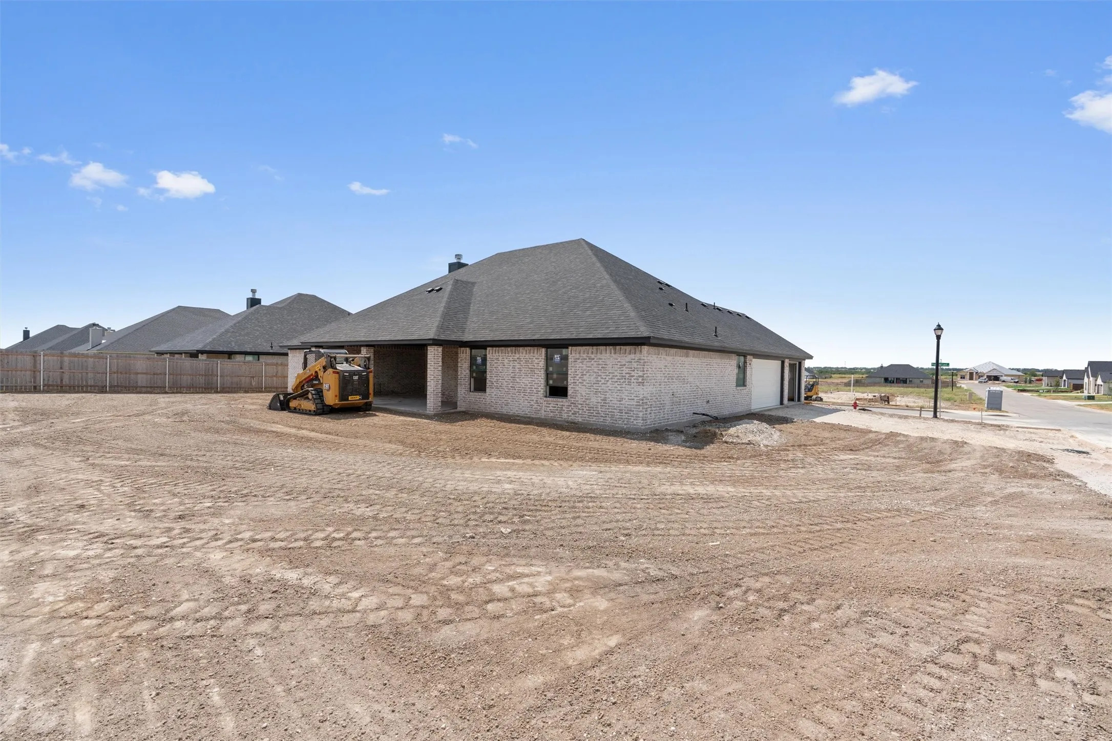 New construction featuring a brick exterior, covered patio, and a dark shingle roof