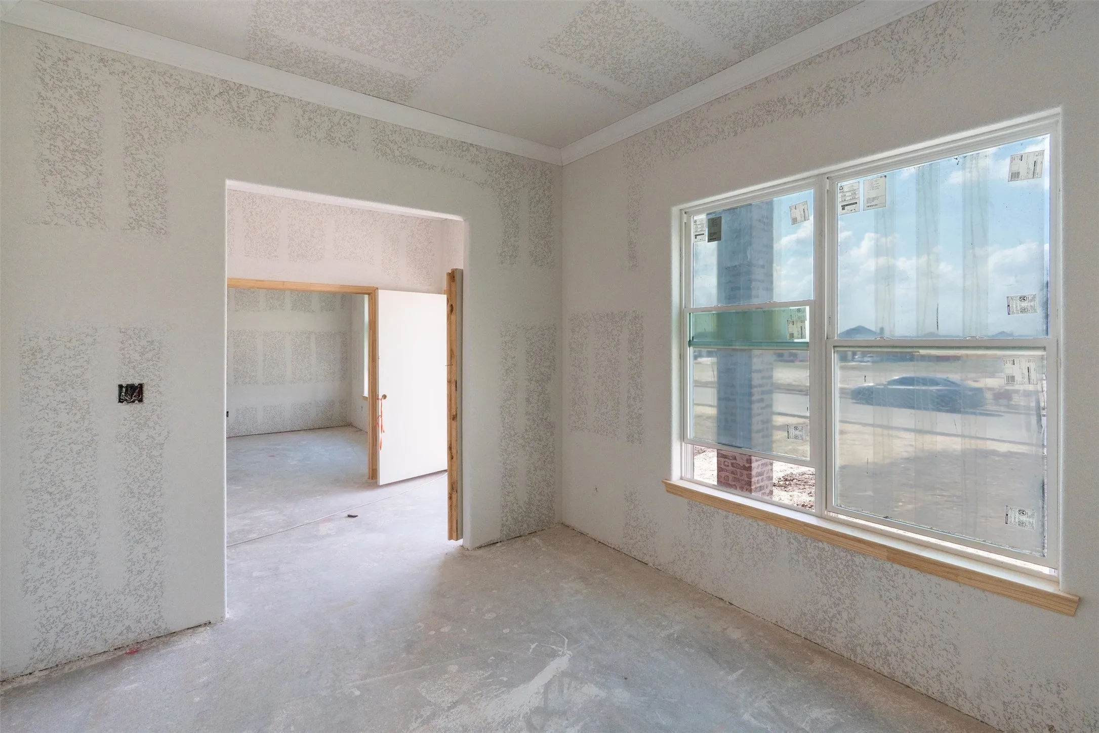 Window with wood-finish sill, unfinished drywall, and crown molding