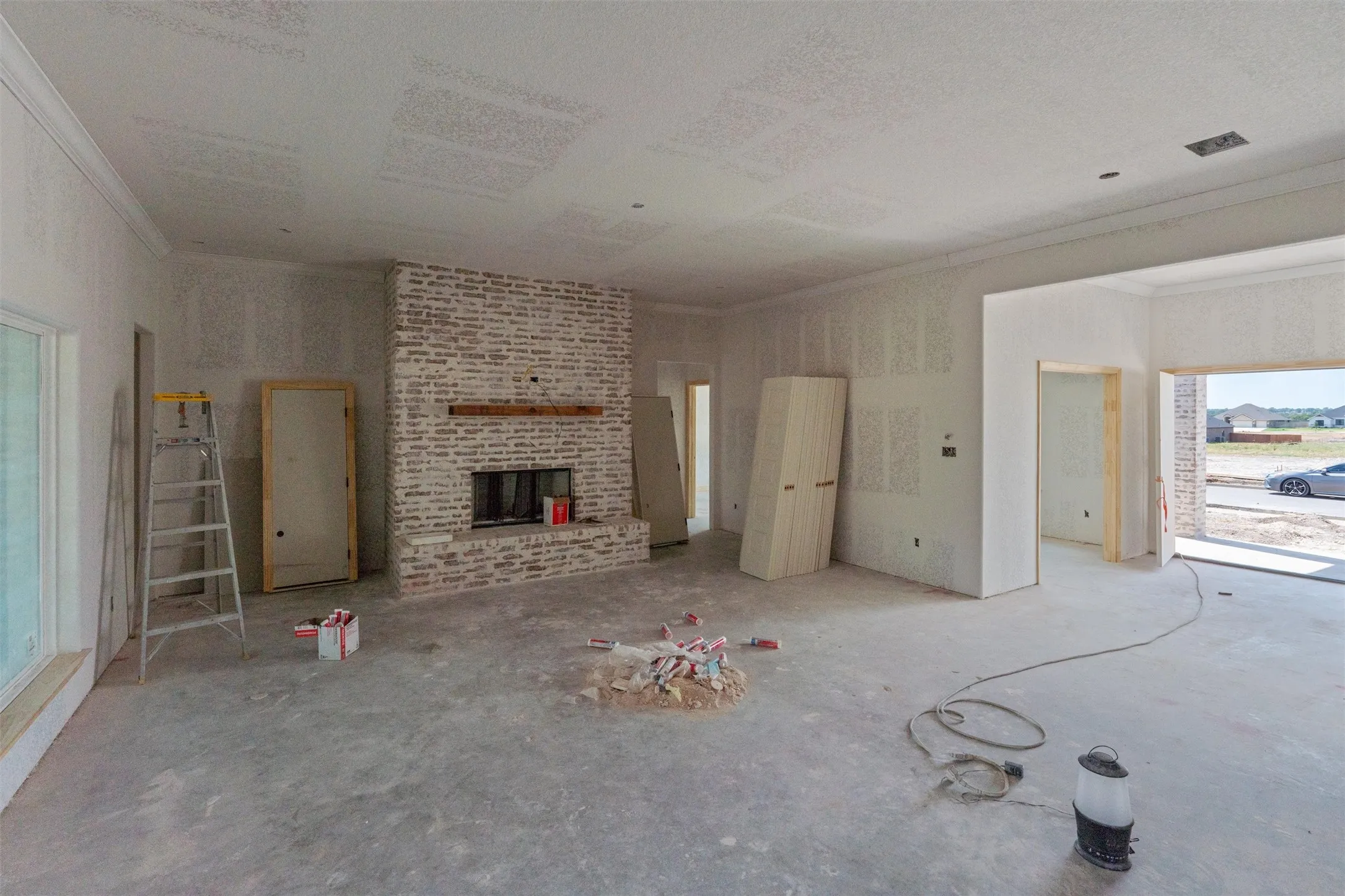 Brick fireplace with wood mantel, crown molding, and an expansive window