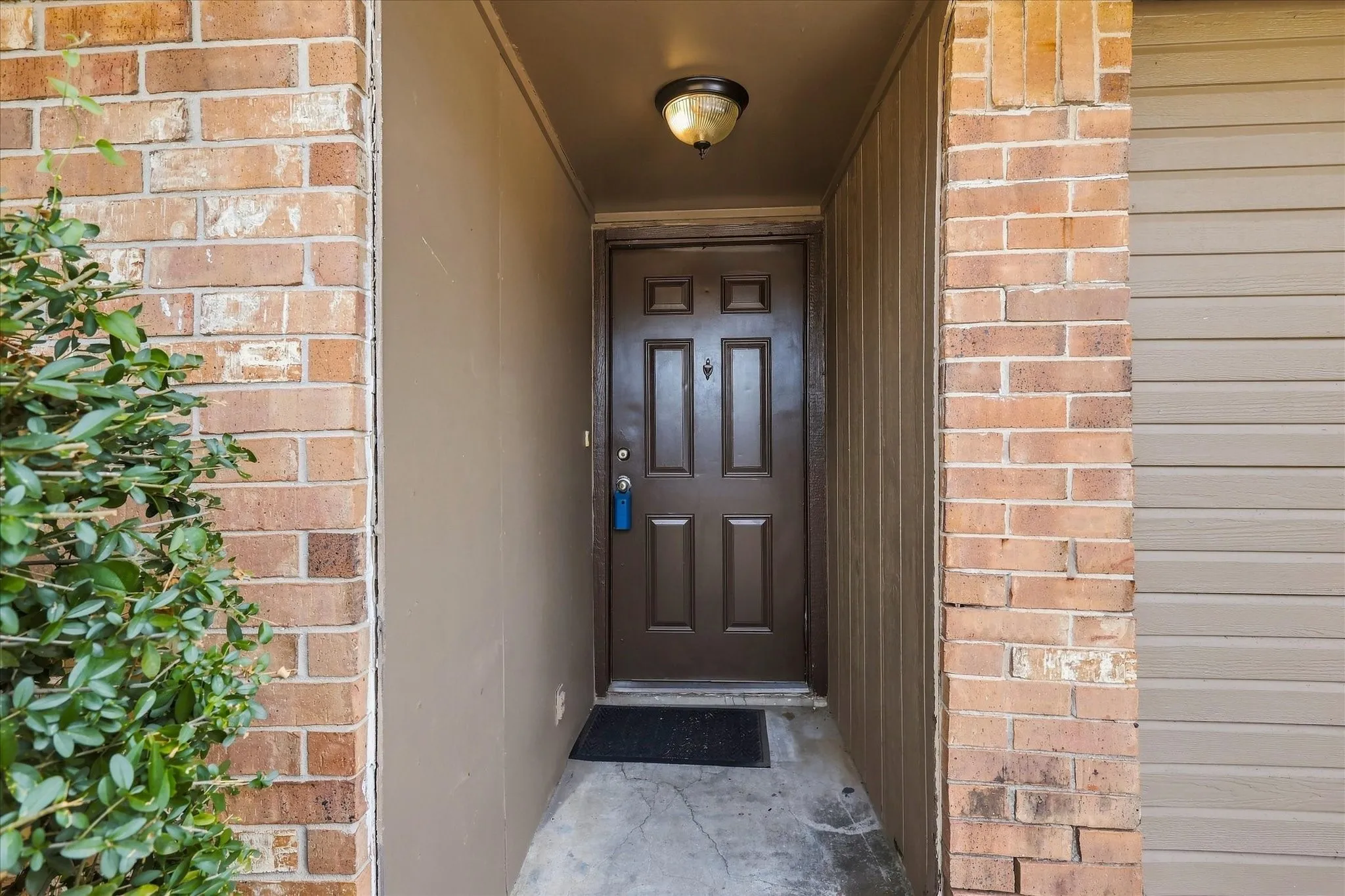 Entryway featuring a panel door, brick facade, and integrated ceiling light fixture