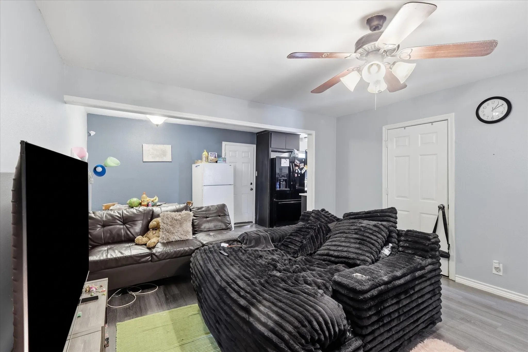 Wood-finish flooring throughout, ceiling fan with integrated lighting, and a white paneled door
