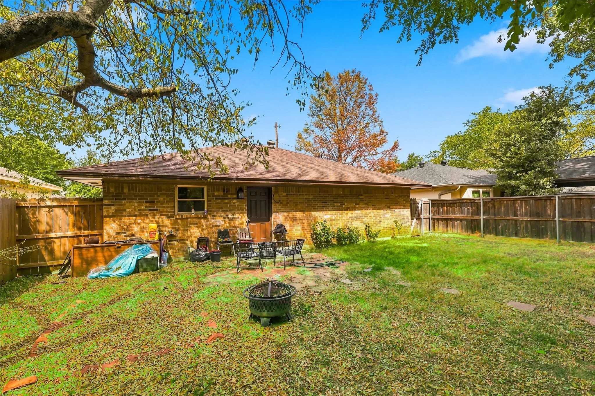 Expansive backyard featuring a brick exterior, shingle roof, wood fencing, and a paved patio area