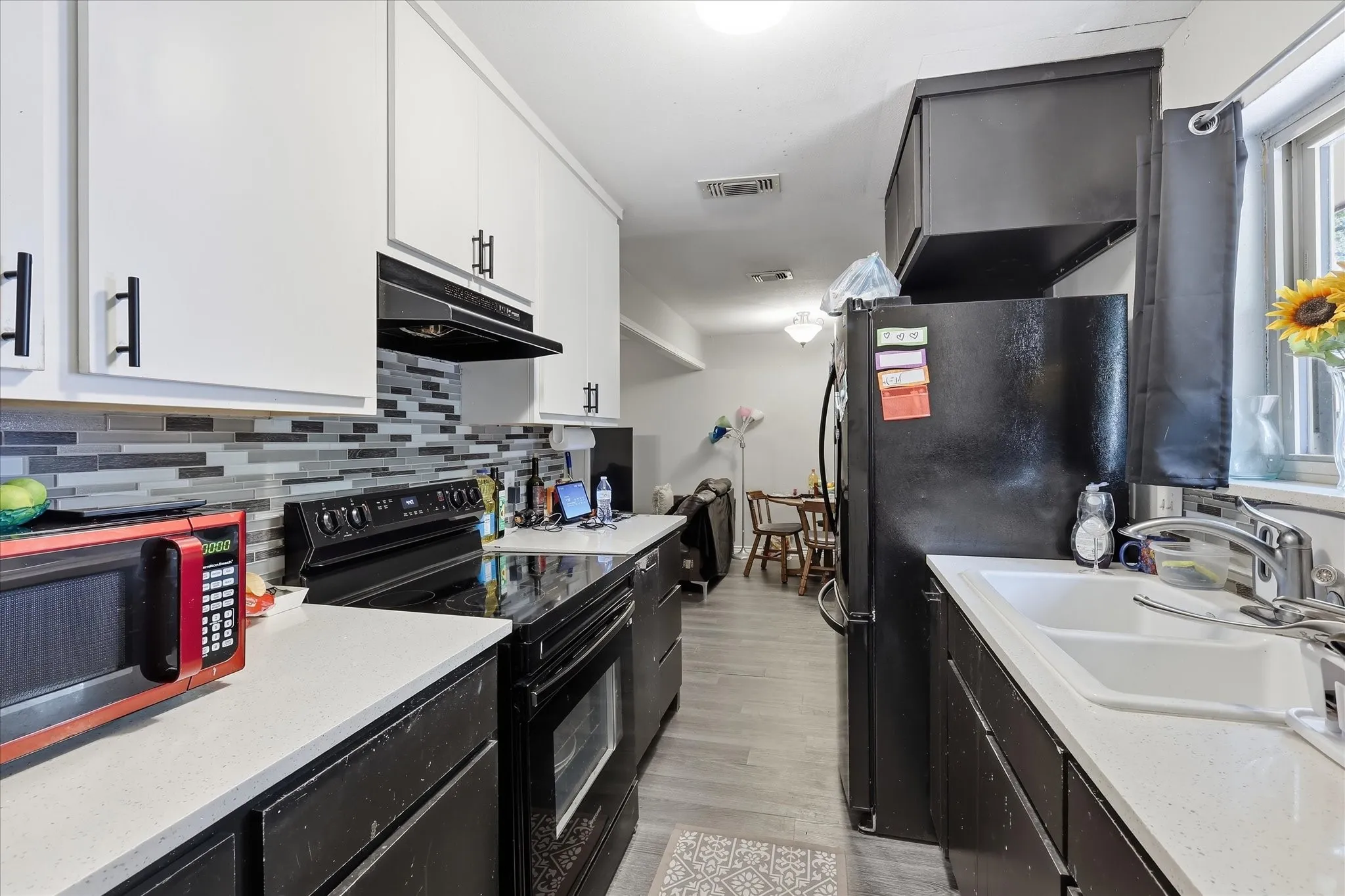 Galley kitchen featuring white upper cabinetry, dark lower cabinetry, and light-toned countertops
