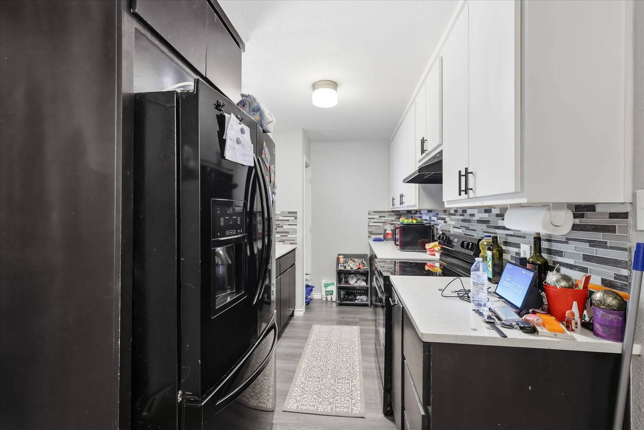 Contemporary kitchen featuring white upper cabinetry and dark lower cabinetry with coordinating hardware
