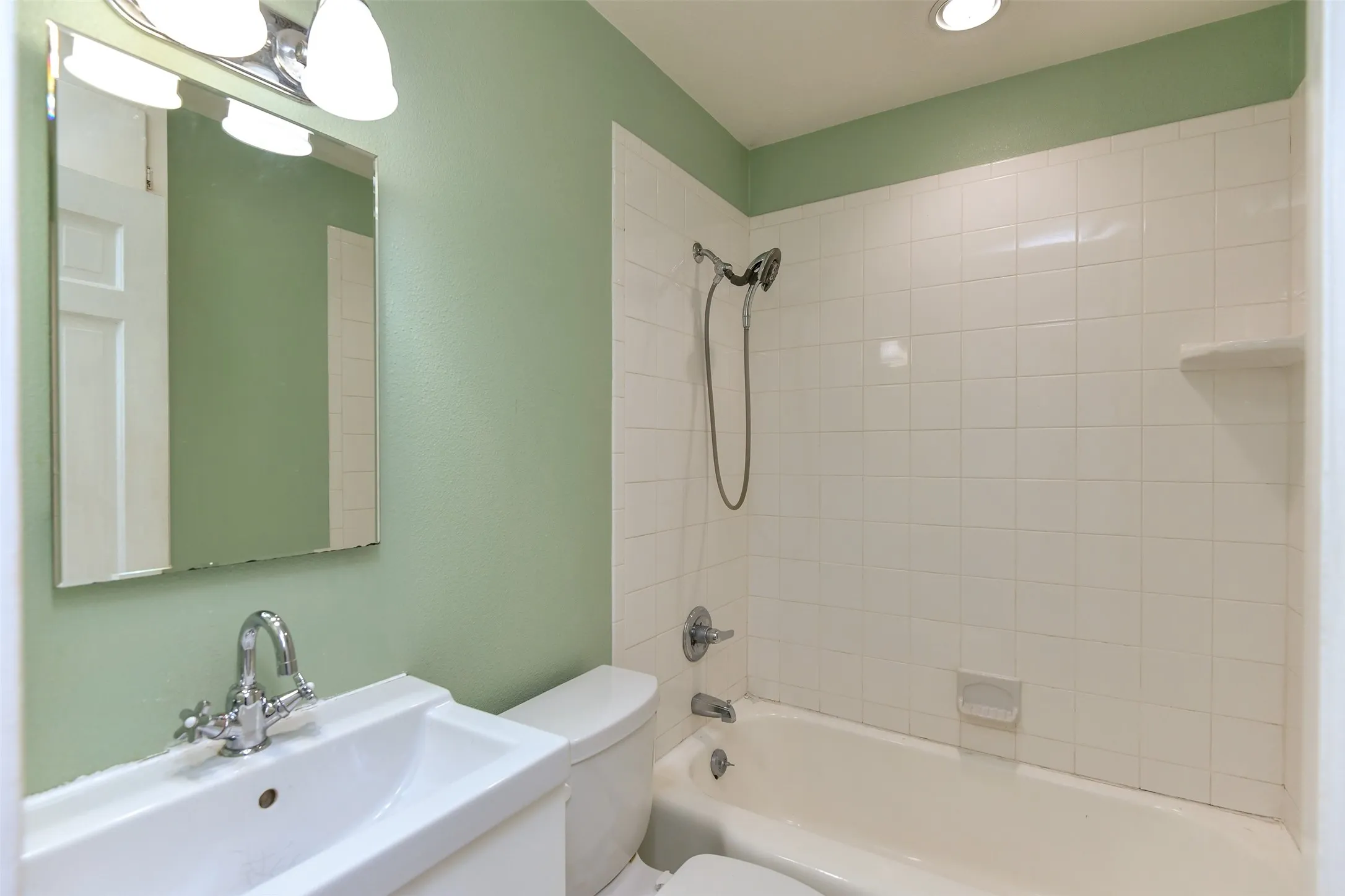 Full bathroom featuring tiled shower / bath combo, toilet, and sink