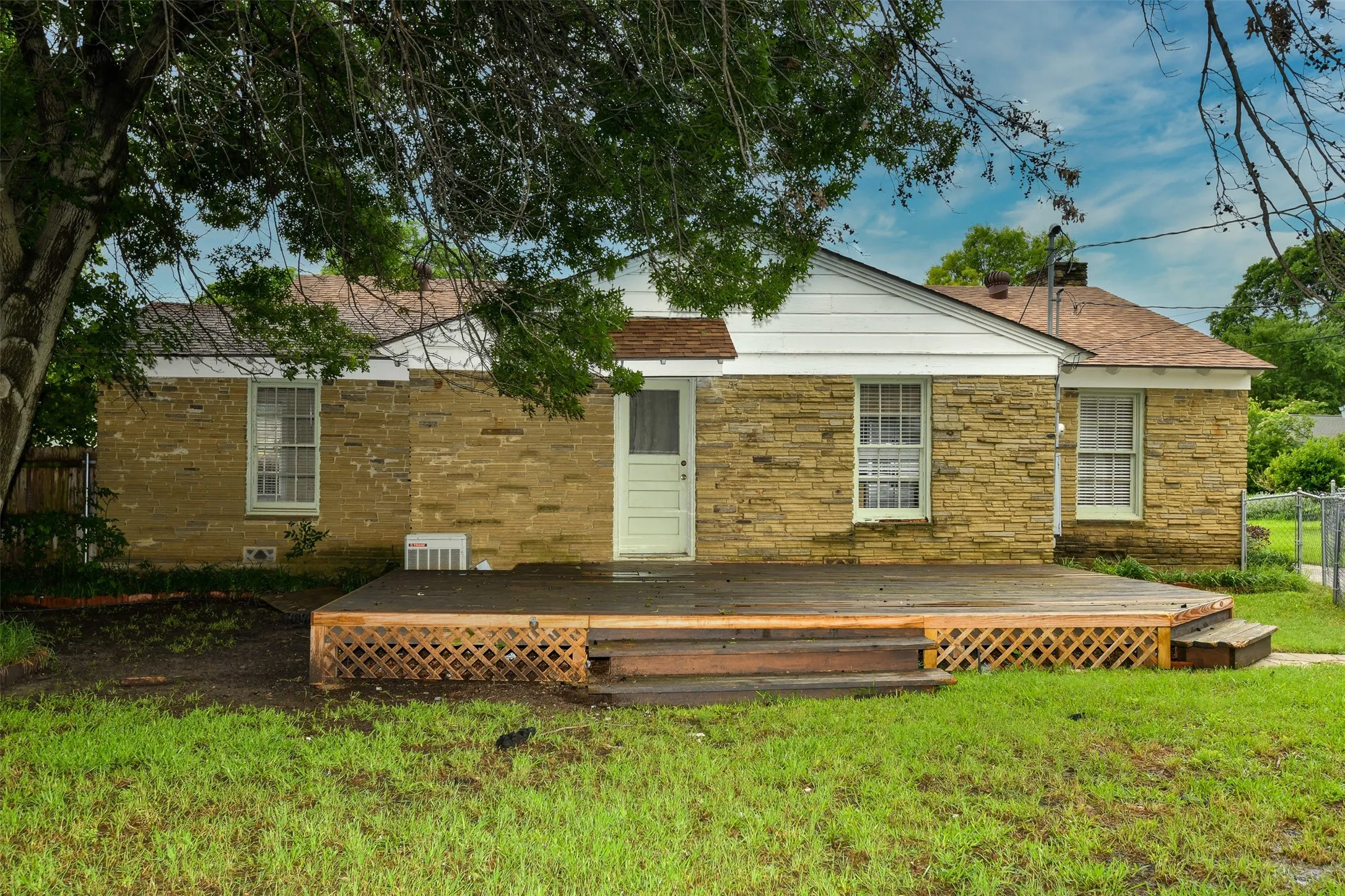 Back of property featuring central air condition unit, a wooden deck, and a yard