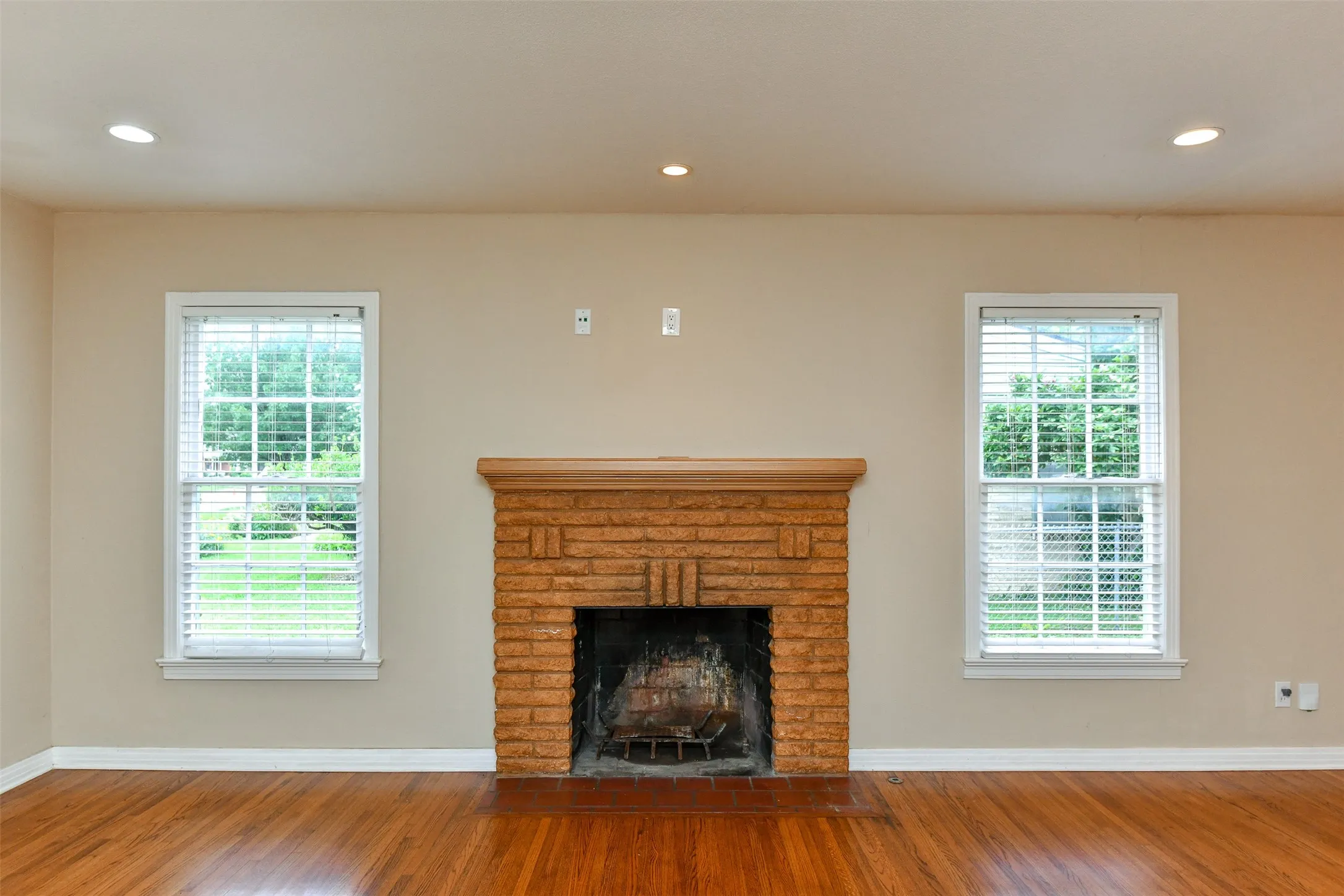 Unfurnished living room featuring hardwood / wood-style flooring, a healthy amount of sunlight, and a fireplace