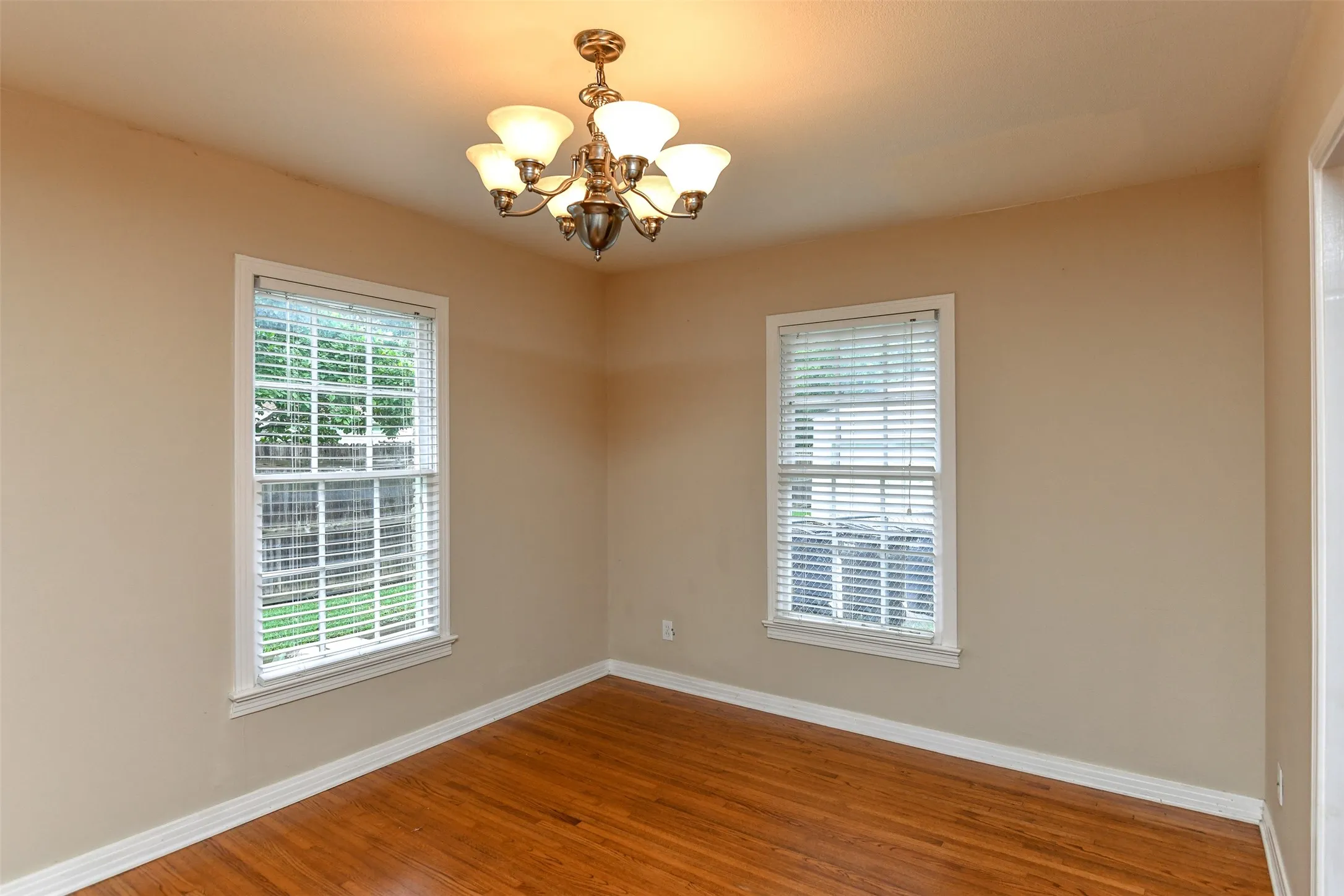 Spare room with wood-type flooring and a chandelier
