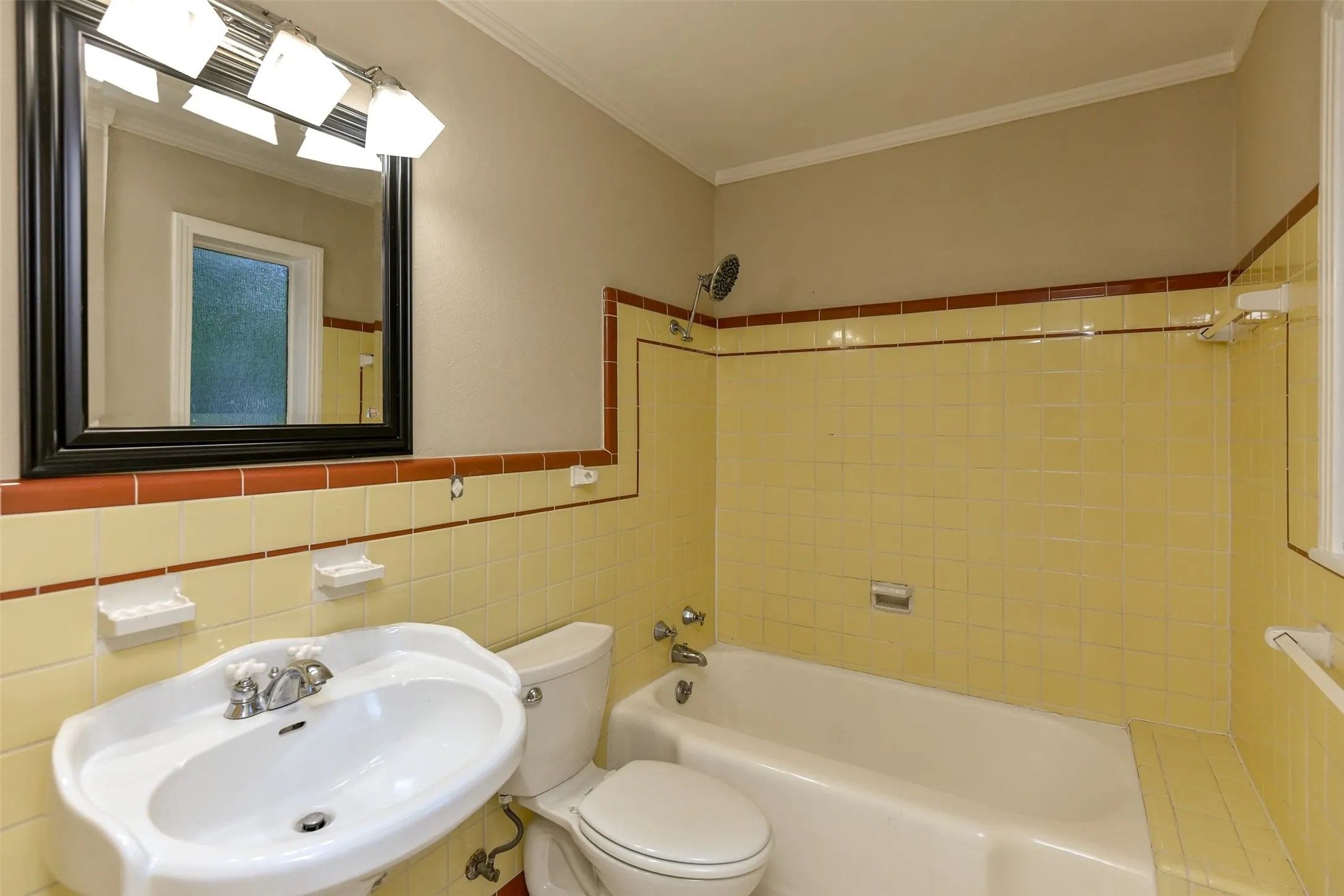 Full bathroom featuring sink, ornamental molding, toilet, tile walls, and tiled shower / bath