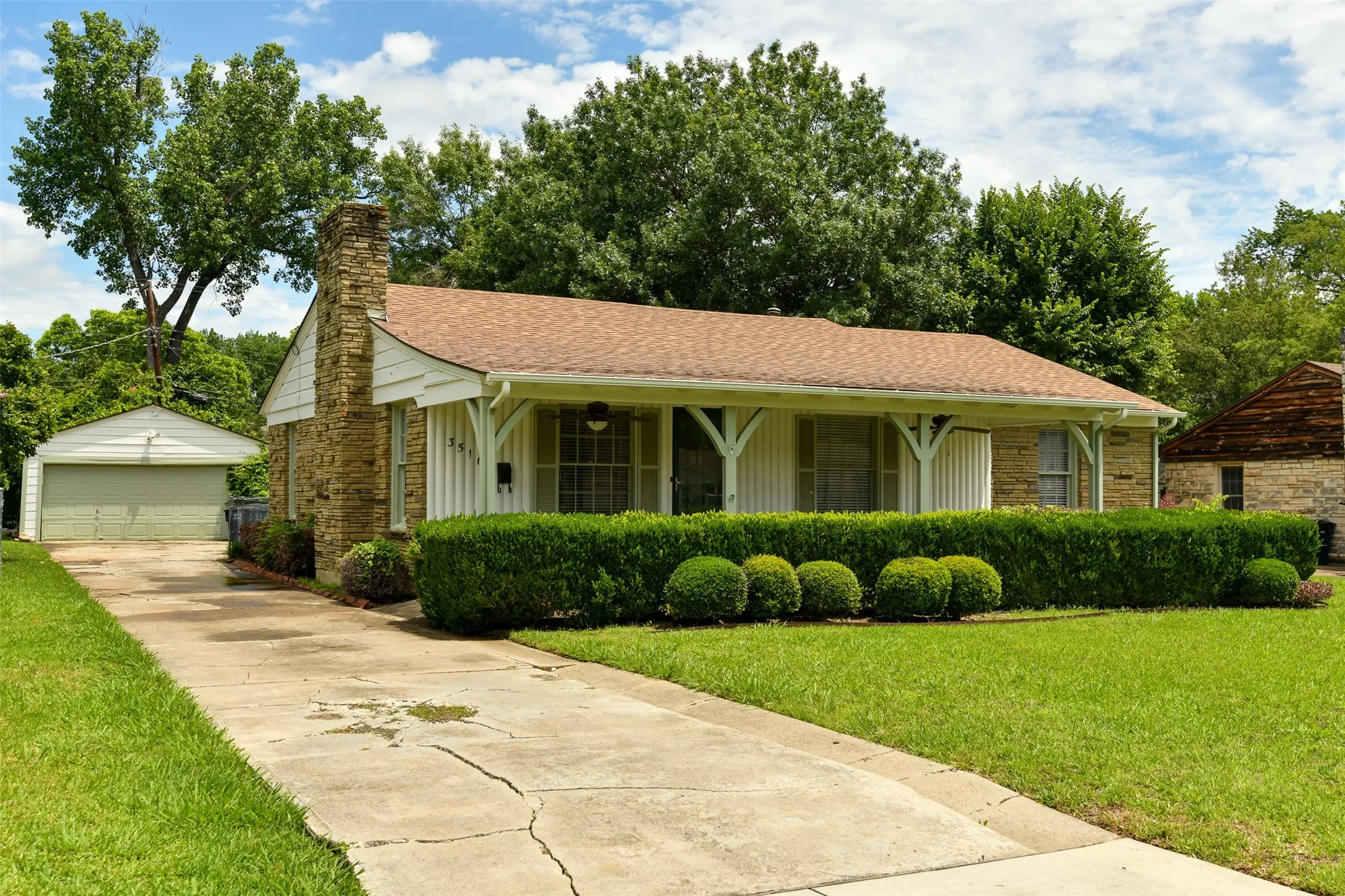 View of front of home featuring an outbuilding, a porch, a garage, and a front yard