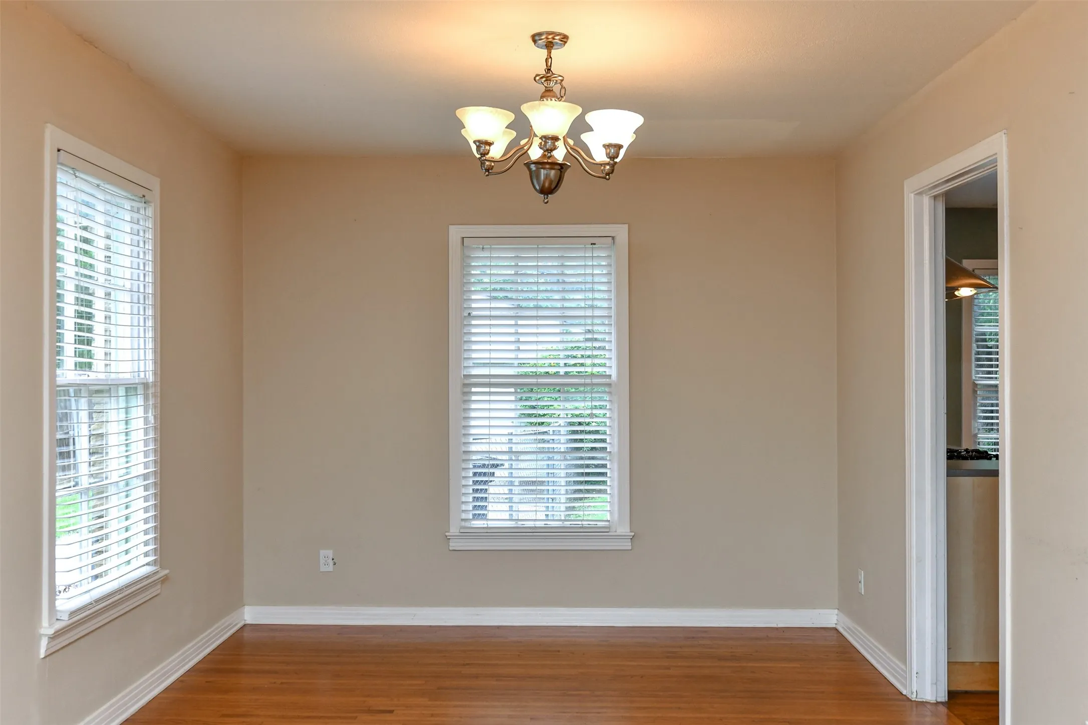 Spare room featuring wood-type flooring and an inviting chandelier