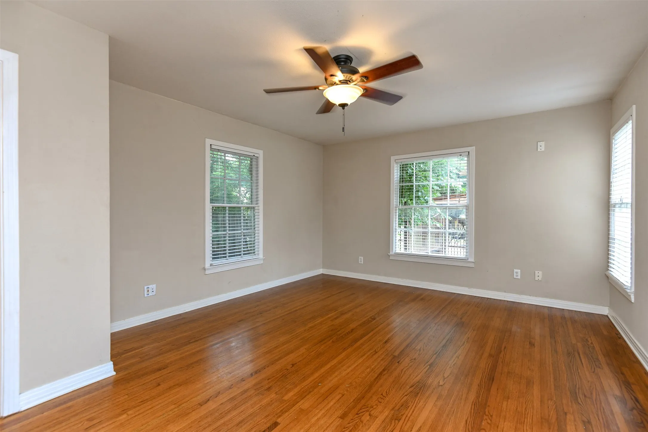 Empty room with ceiling fan and dark hardwood / wood-style flooring