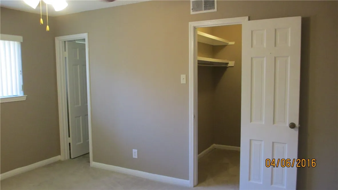 Master bedroom with ceiling fan and walk in closet