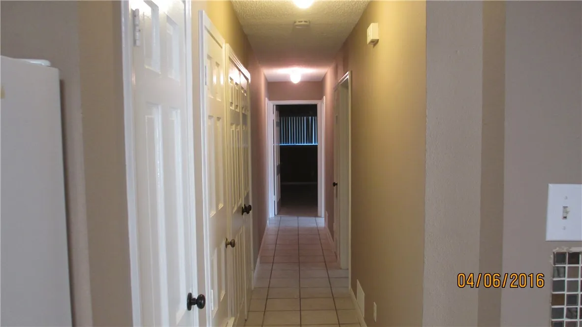 View down the long hall from the kitchen shows laundry closet and linen closet