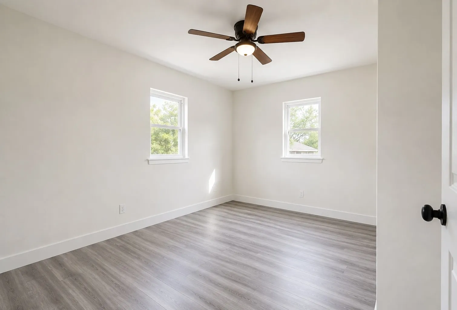 Wood-finish flooring, white walls, and a ceiling fan with integrated lighting