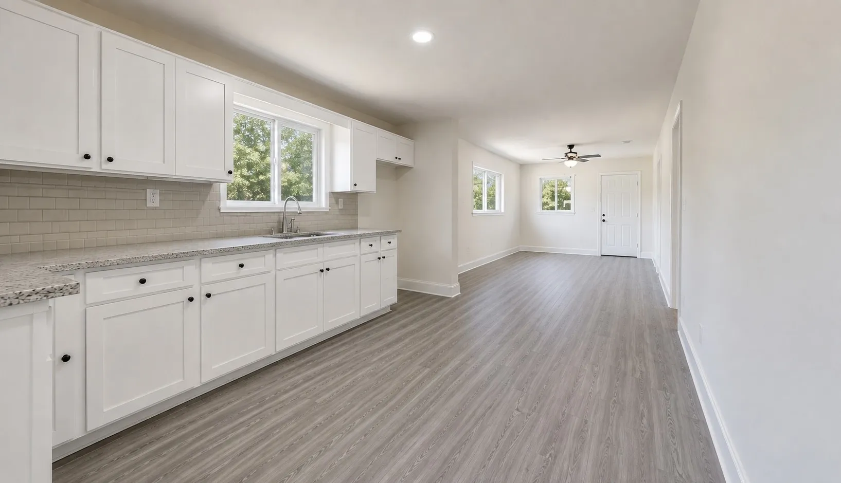 Kitchen featuring white cabinetry with black hardware, light-toned countertops, and a subway tile backsplash