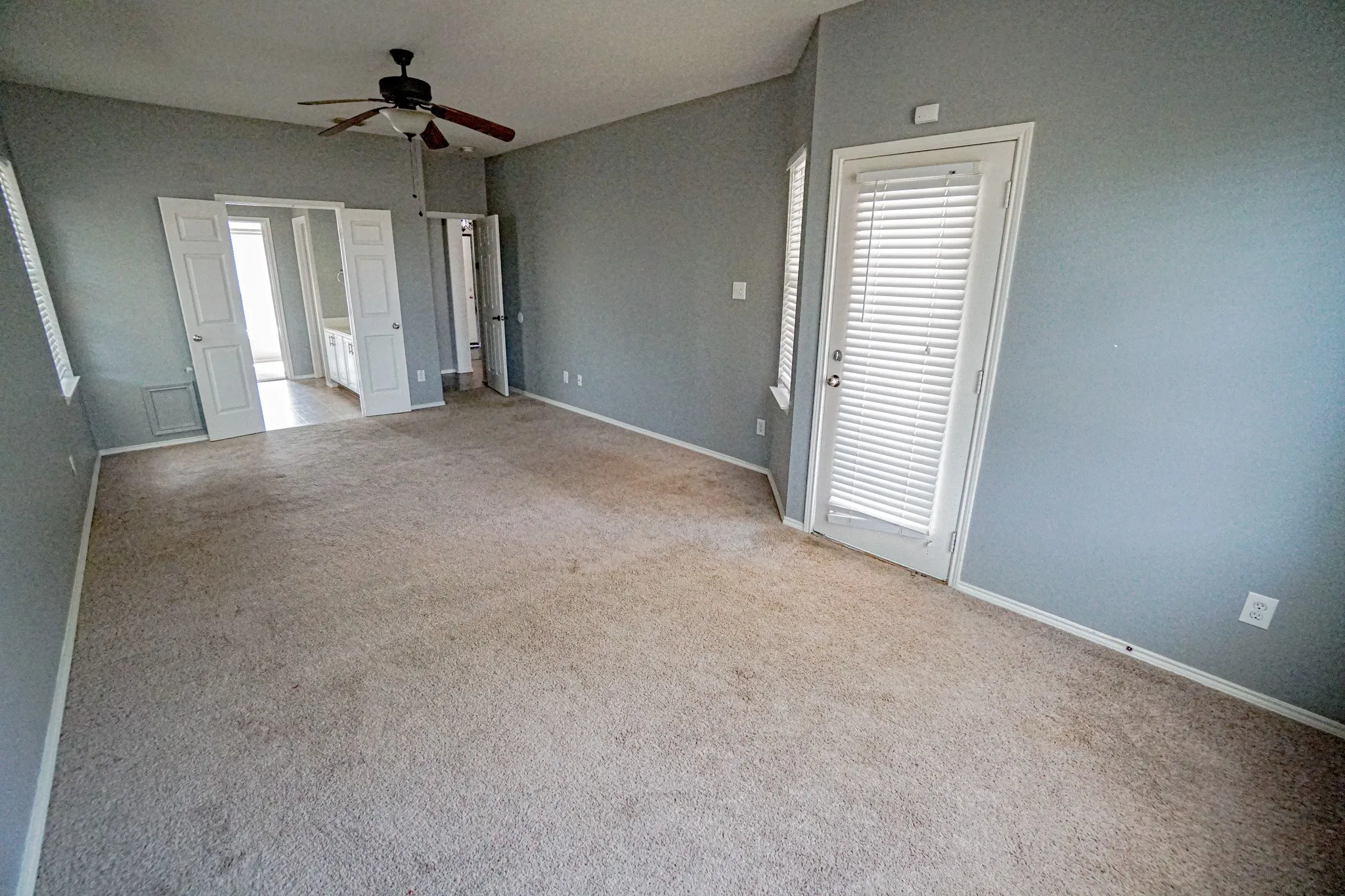 Primary BR suite with a ceiling fan, a white door with integrated blinds, and an entryway with bifold peted roomdoors