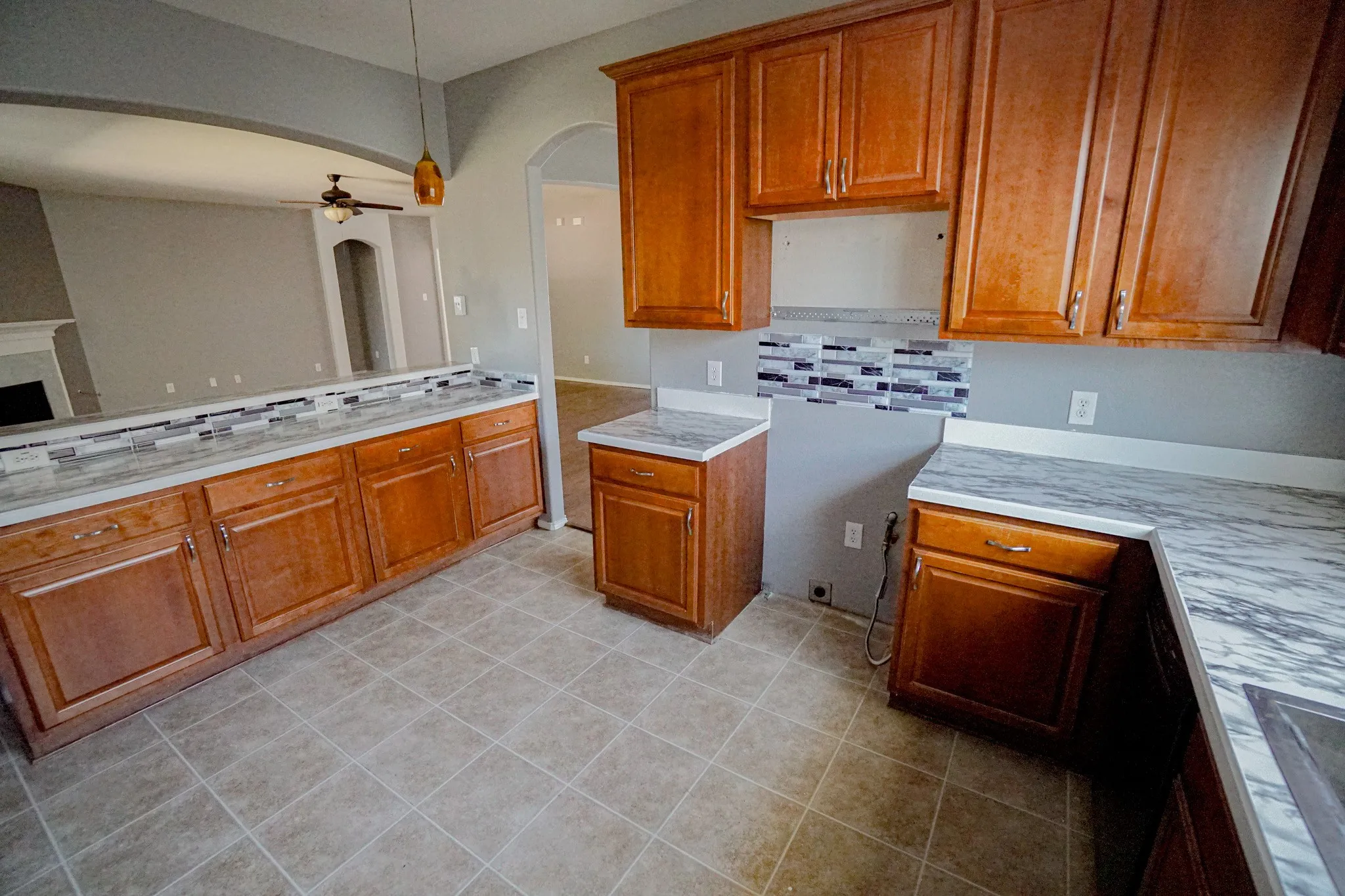 Kitchen with wood cabinetry, light-toned countertops, and a mosaic tile backsplash