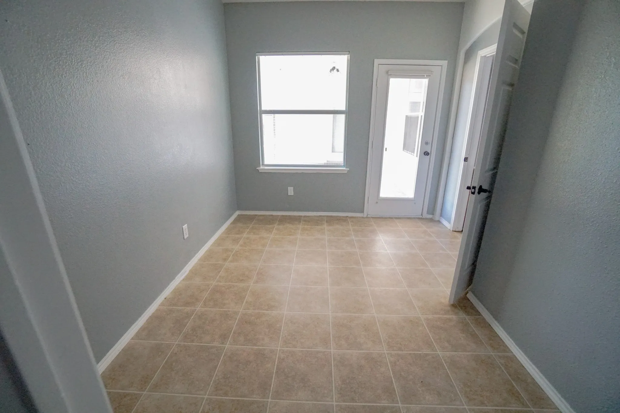 Tile flooring, neutral wall tones, white trim, window, and exterior door with glass paneling
