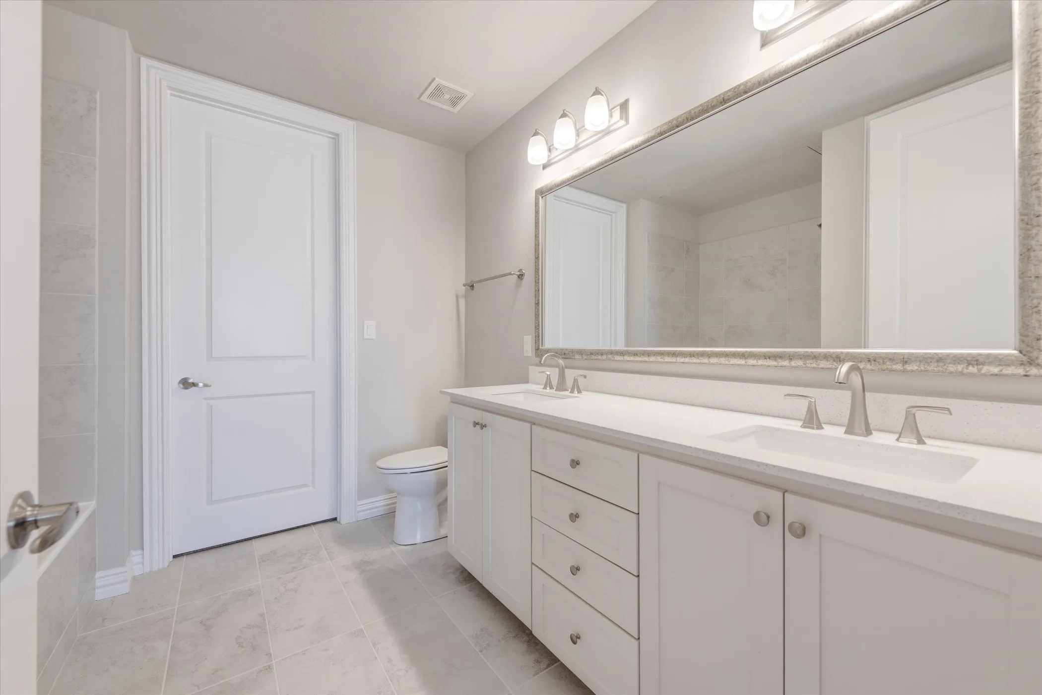 Double vanity with undermount sinks and brushed nickel fixtures, set against a full-width mirror with an ornate frame