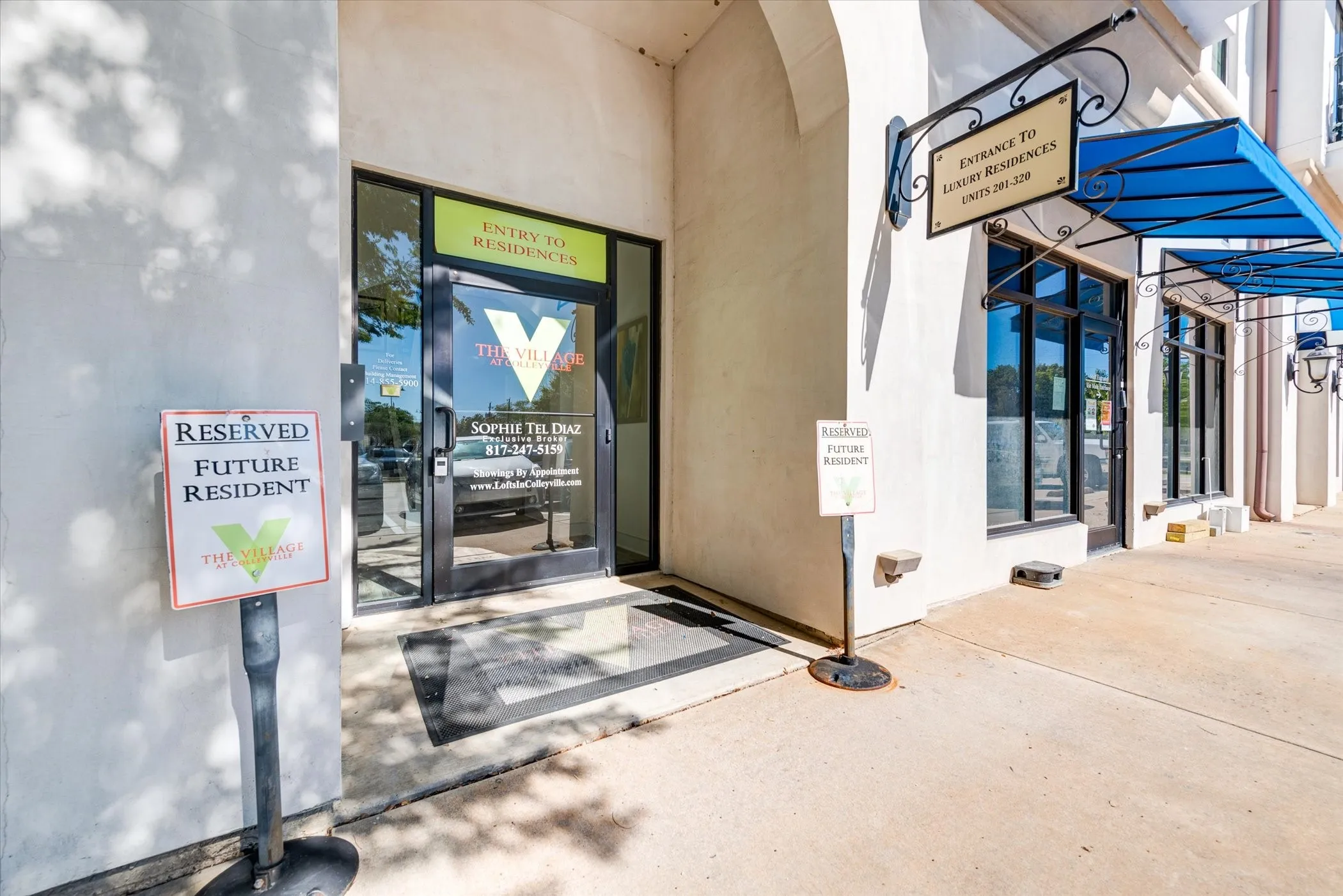 Entry to residences featuring full-lite glass doors, wrought iron sign bracket, and blue fabric awnings