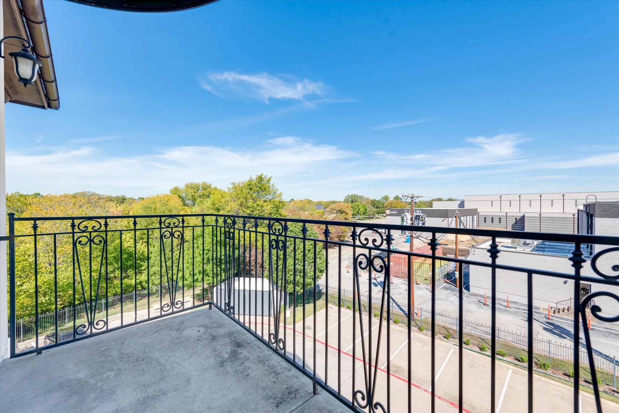 Balcony with ornate black metal railing and concrete flooring