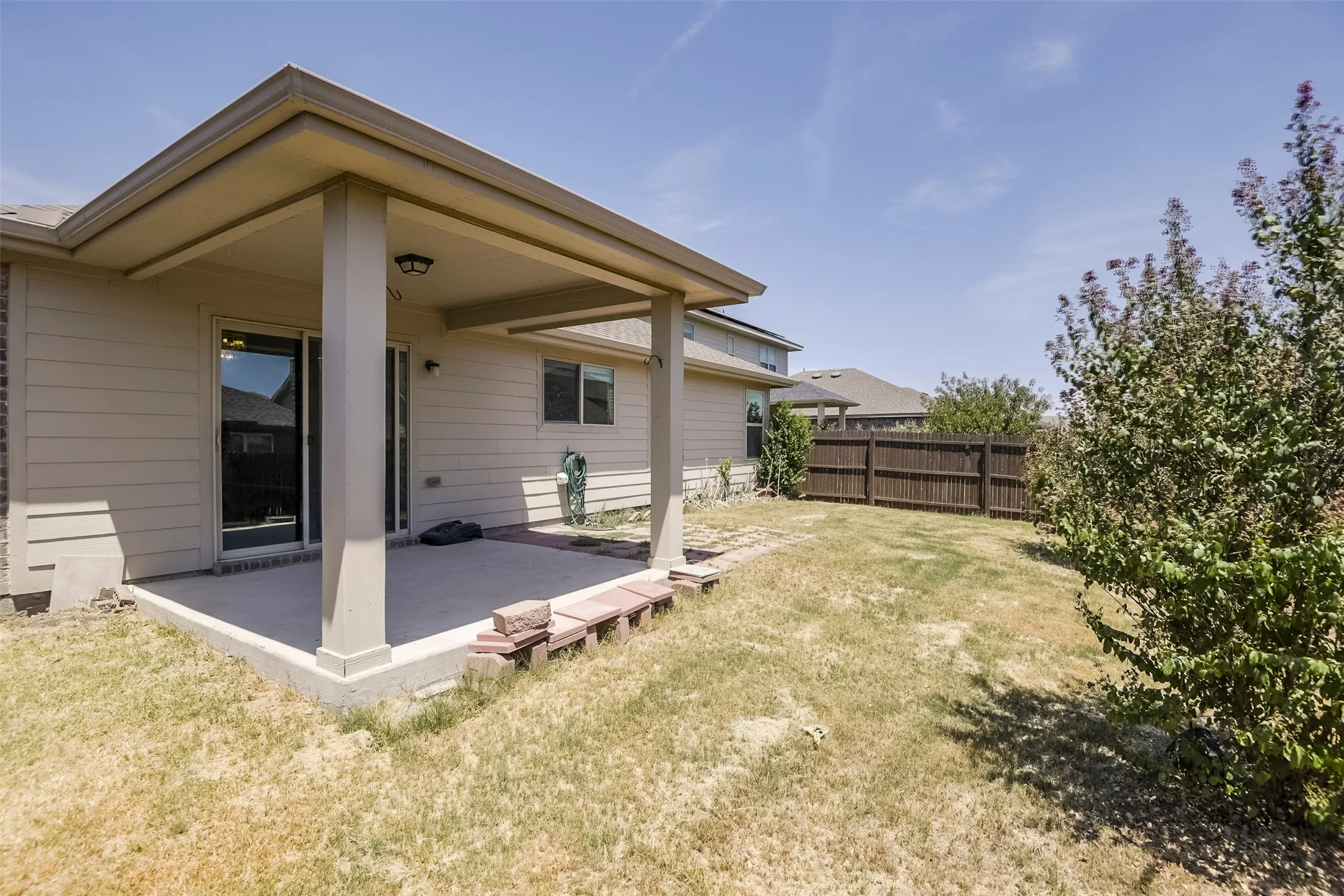 Covered patio with a concrete slab, sliding glass door, and exterior lighting