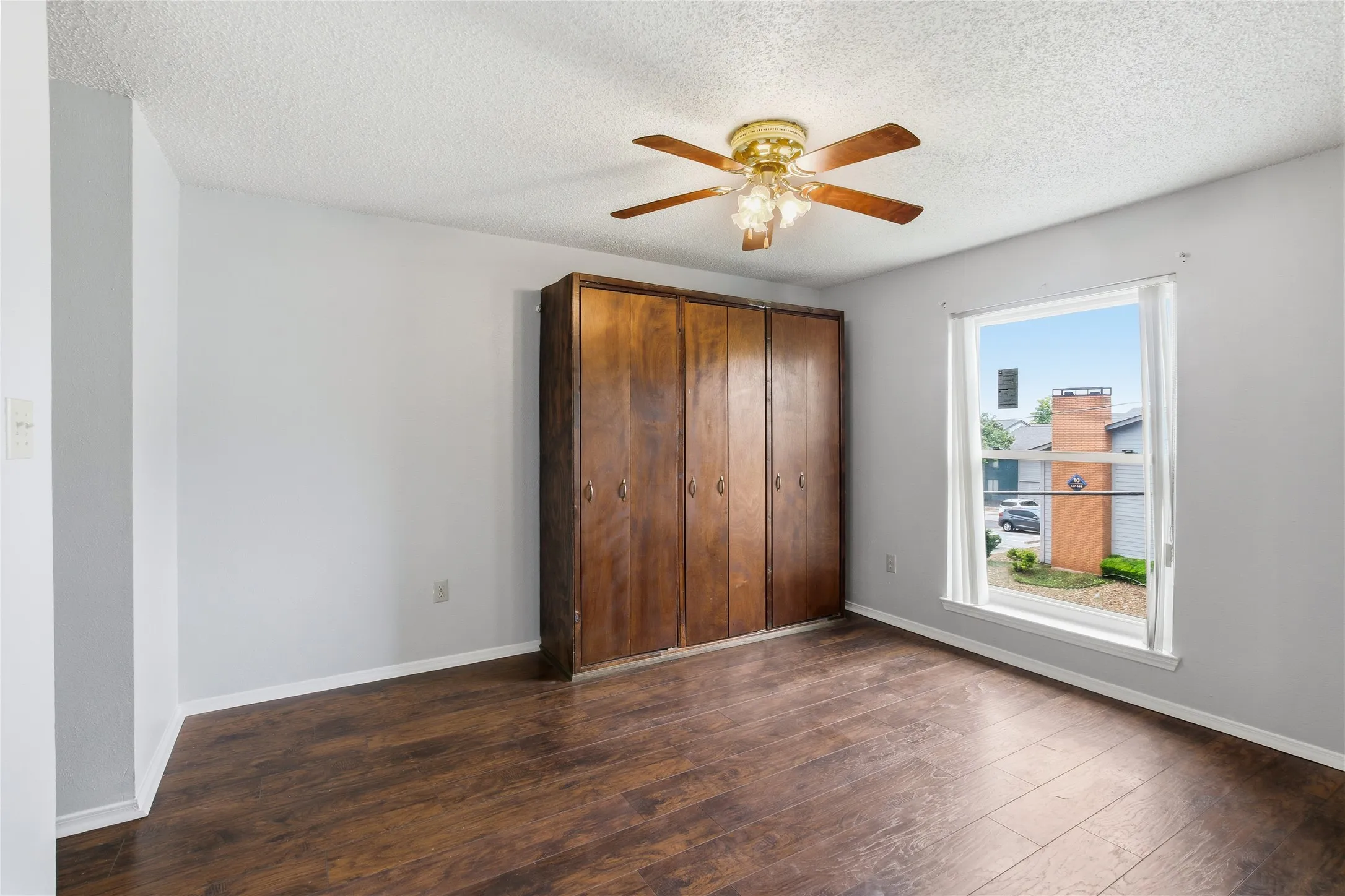Wood-finish flooring, built-in storage cabinetry, ceiling fan with light fixture, and a large window