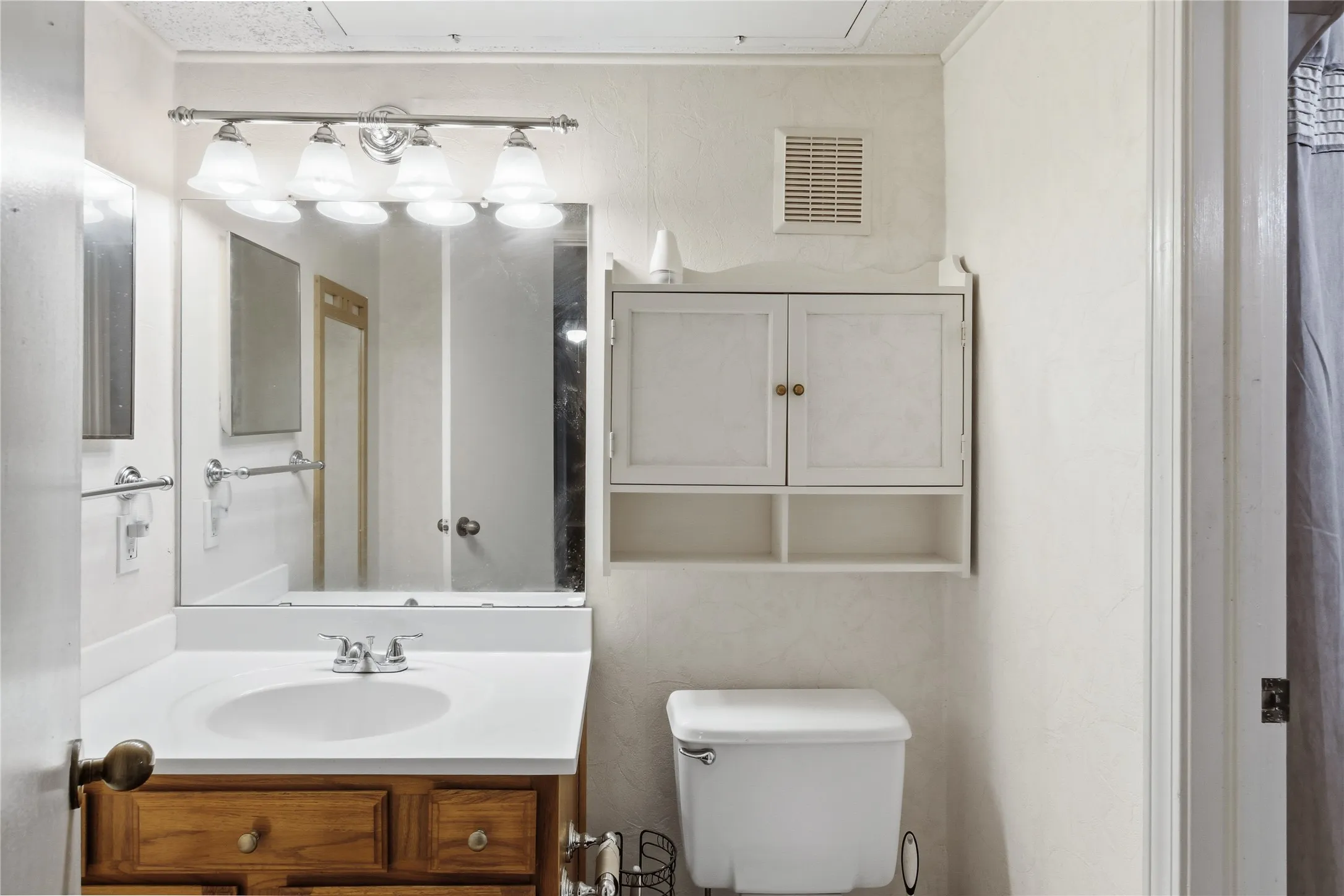 White vanity with a wood-finish base, integrated sink, and chrome faucet