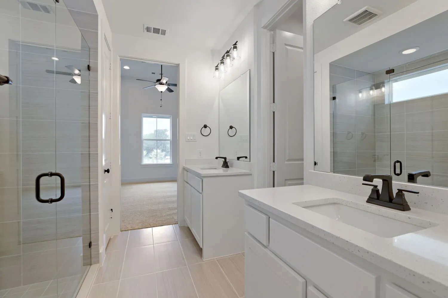 Dual vanities with white countertops, integrated sinks, and black fixtures
