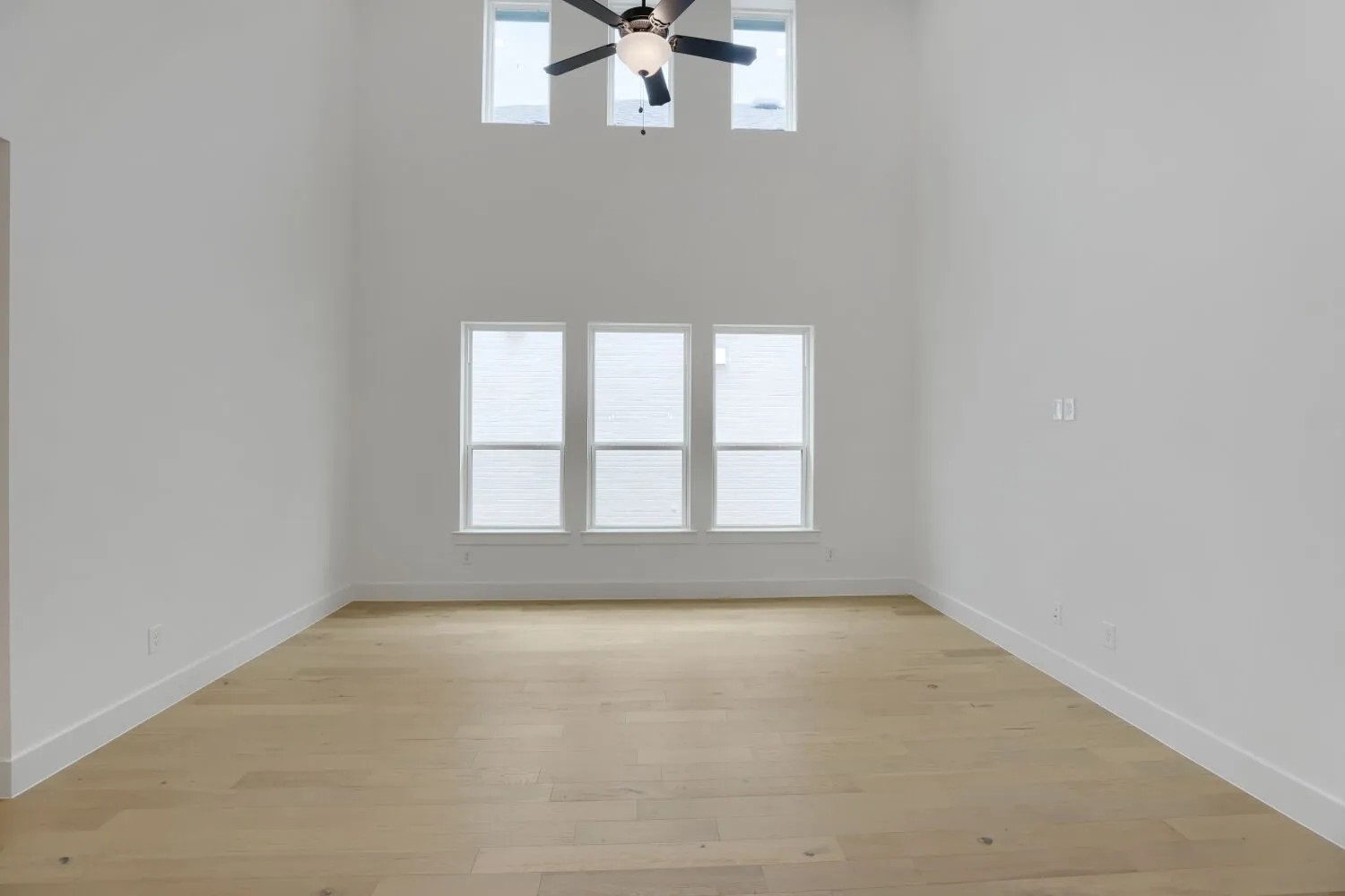 Two-story family room with ceiling fan and transom windows