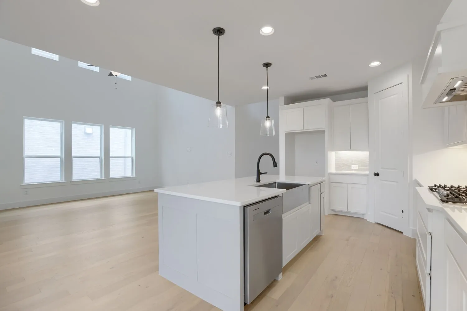 Kitchen island with a farmhouse sink and matte black faucet, integrated dishwasher, and pendant lighting
