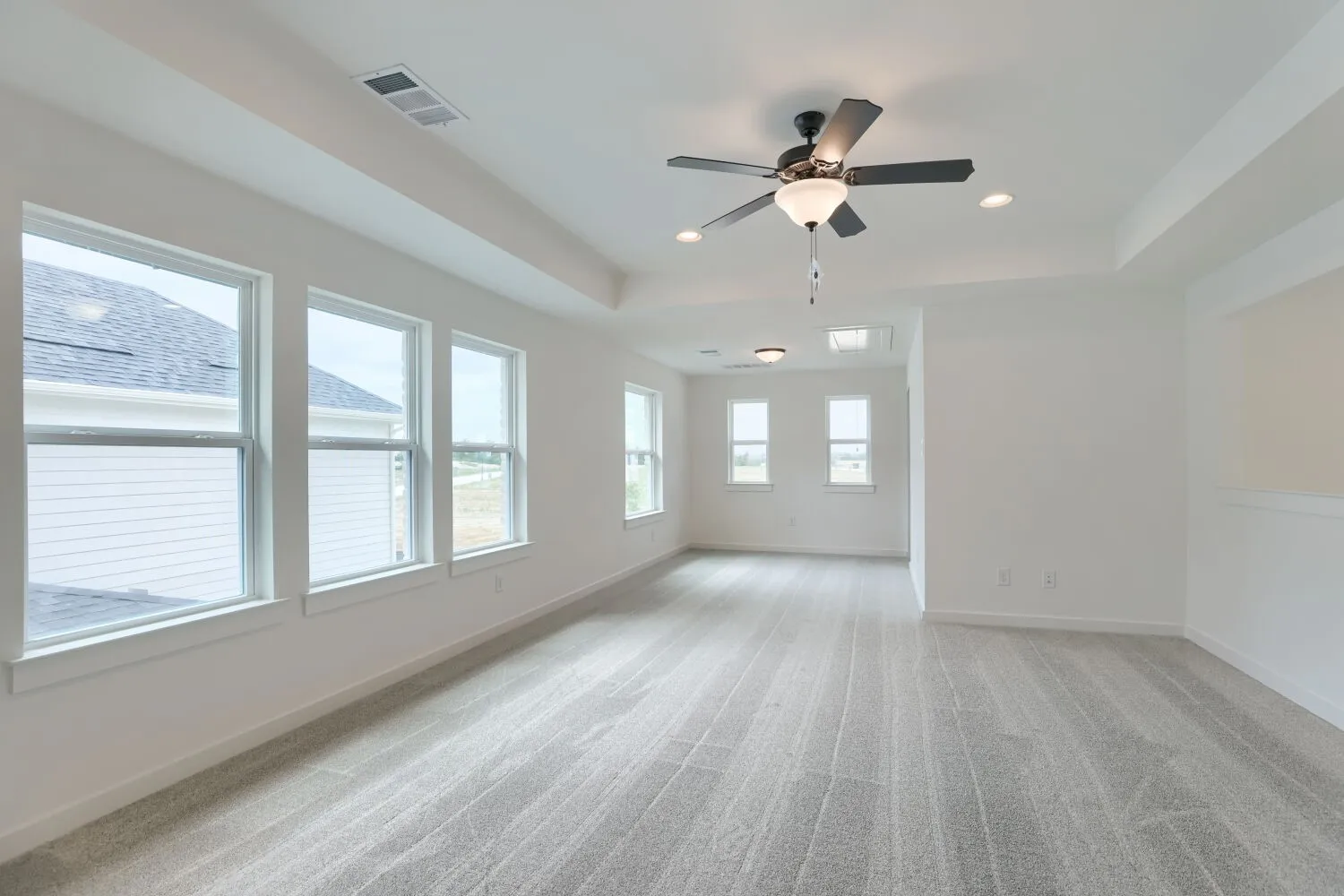 Game room with tray ceiling, recessed lighting, ceiling fan with light fixture, multiple windows, and light gray carpeted flooring