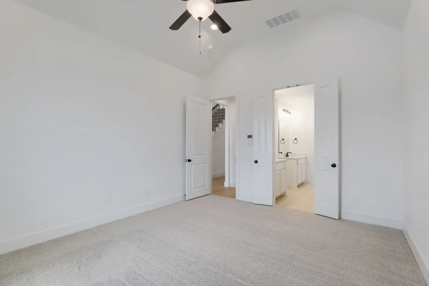 Vaulted ceiling with a ceiling fan, light gray carpet, and two panel doors