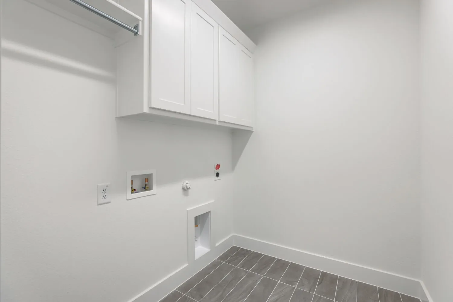 Built-in cabinetry, laundry hookups, white baseboards, and tile flooring