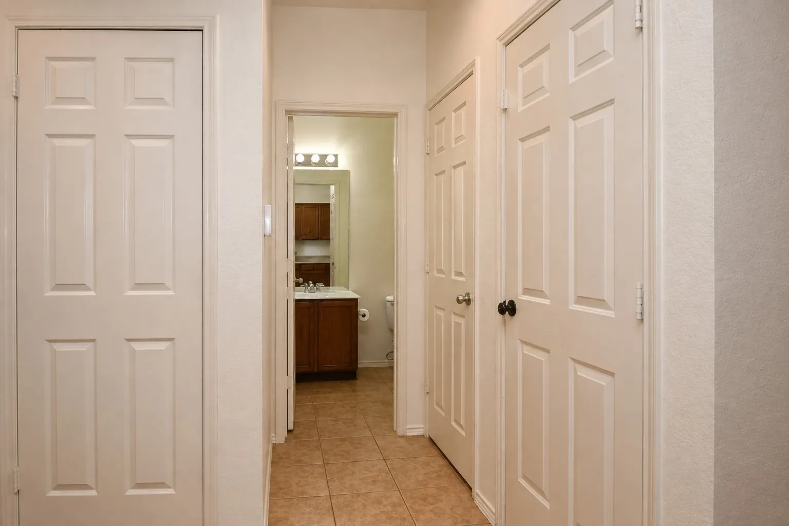Hallway featuring neutral paint, panel doors, and tile flooring