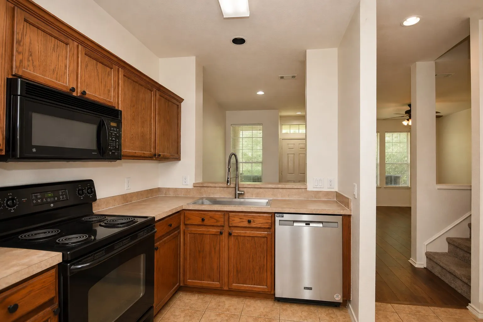 Kitchen featuring wood-finish cabinetry, black appliances, a stainless steel dishwasher, and tile flooring