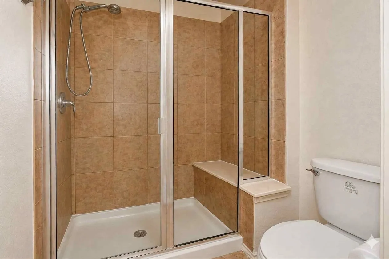Enclosed shower with a built-in bench, tiled walls, and a white shower base